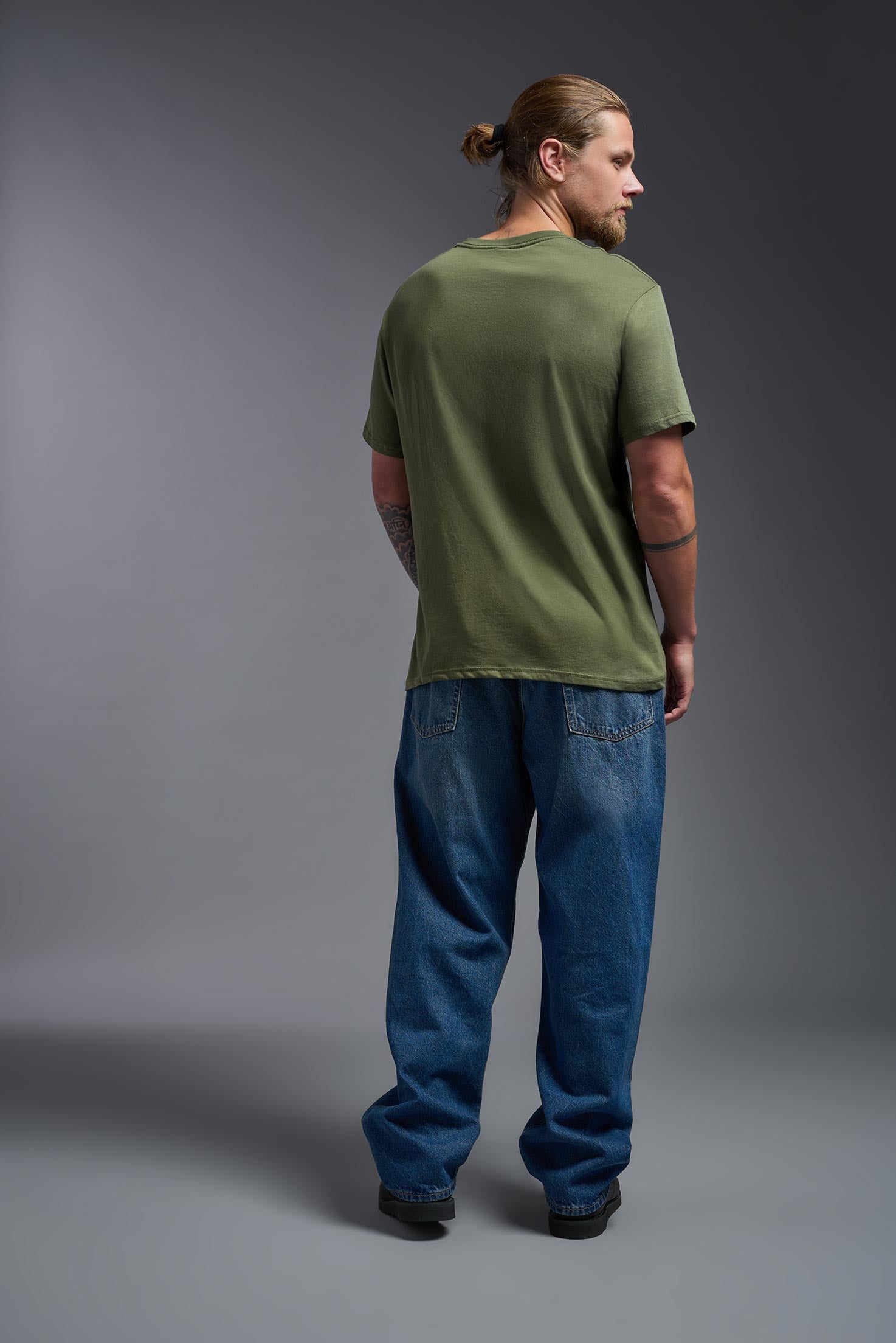 A male model wearing the unisex Americana Cotton Soft Tee in the color military green, made from 100% combed ring-spun USA-grown cotton, showing the classic fit from a back view. This premium shirt is Made in the USA. #military-green