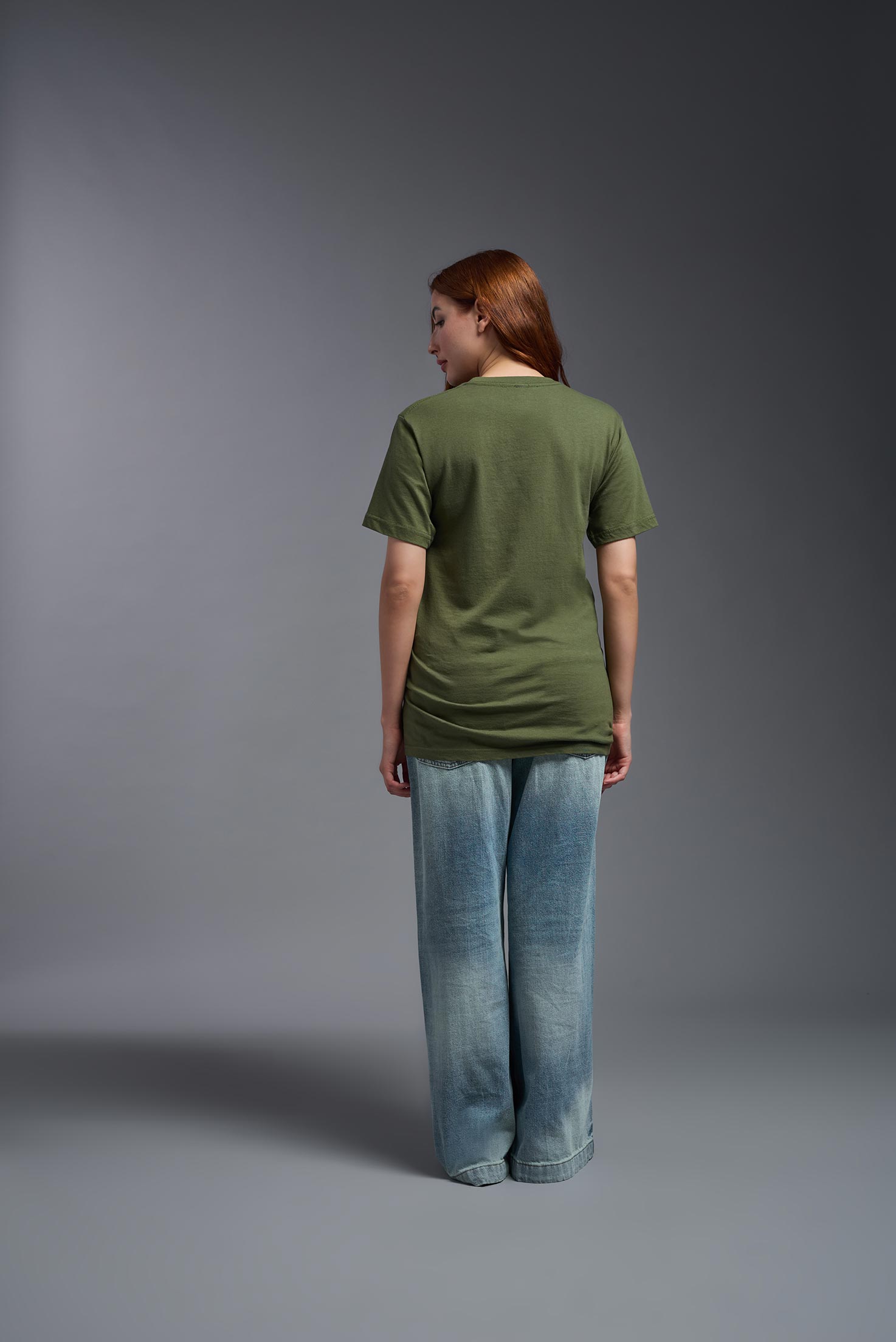 A female model wearing the unisex Americana Cotton Soft Tee in the color military green, made from 100% combed ring-spun USA-grown cotton, showing the classic fit from a back view. This premium shirt is Made in the USA. #military-green
