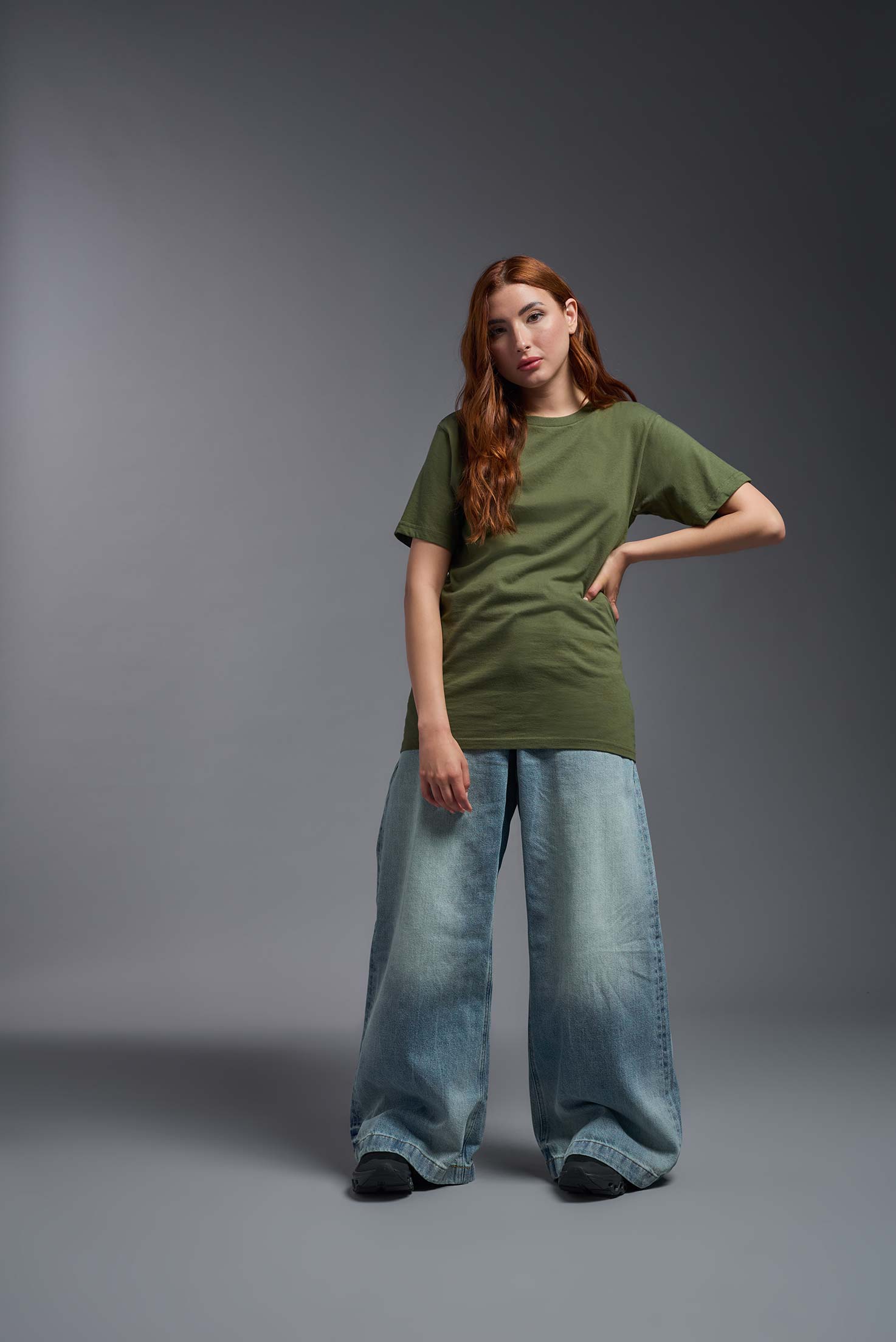 A female model wearing the unisex Americana Cotton Soft Tee in the color military green, made from 100% combed ring-spun USA-grown cotton, showing the classic fit from a front view. This premium shirt is Made in the USA. #military-green