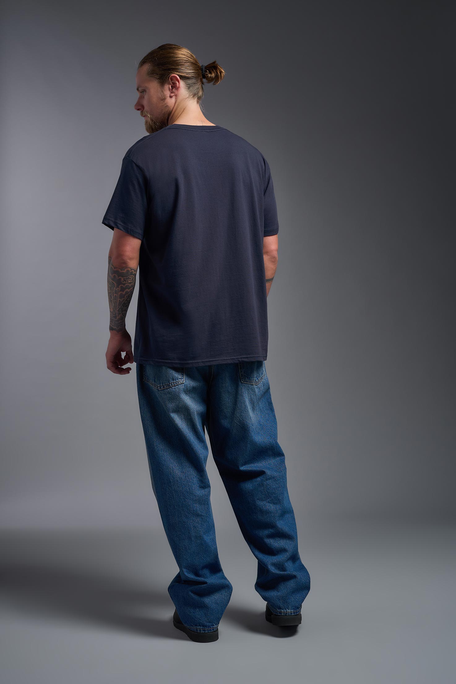 A male model wearing the unisex Americana Cotton Soft Tee in the color navy, made from 100% combed ring-spun USA-grown cotton, showing the classic fit from a back view. This premium shirt is Made in the USA. #navy