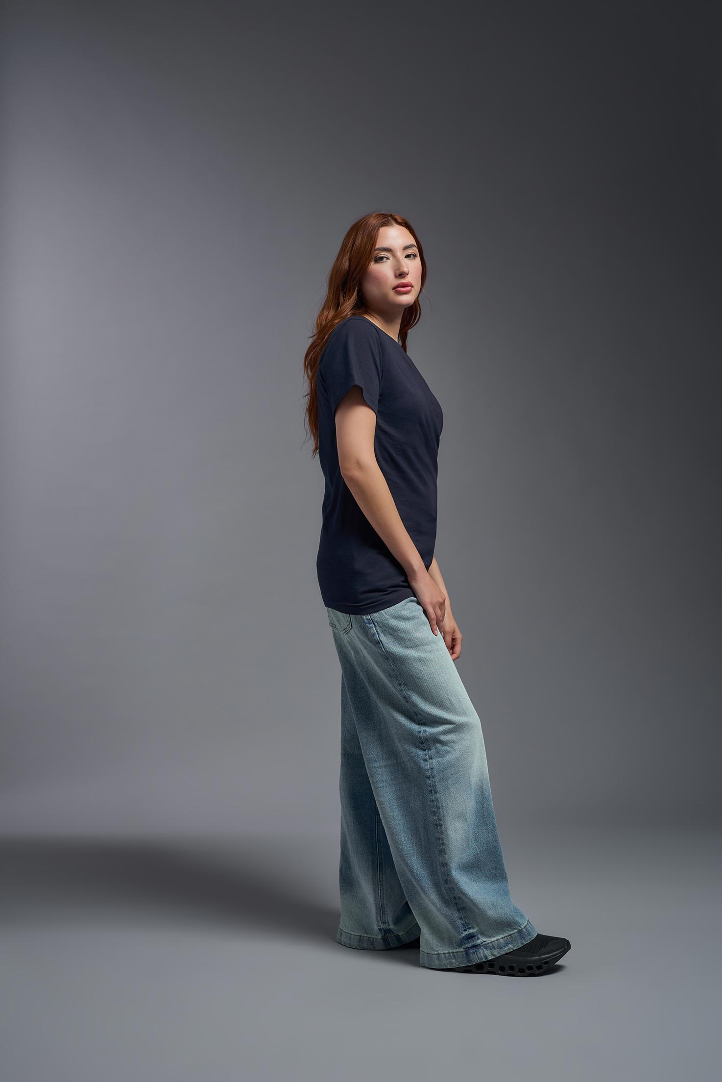 A female model wearing the unisex Americana Cotton Soft Tee in the color navy, made from 100% combed ring-spun USA-grown cotton, showing the classic fit from a side view. This premium shirt is Made in the USA. #navy