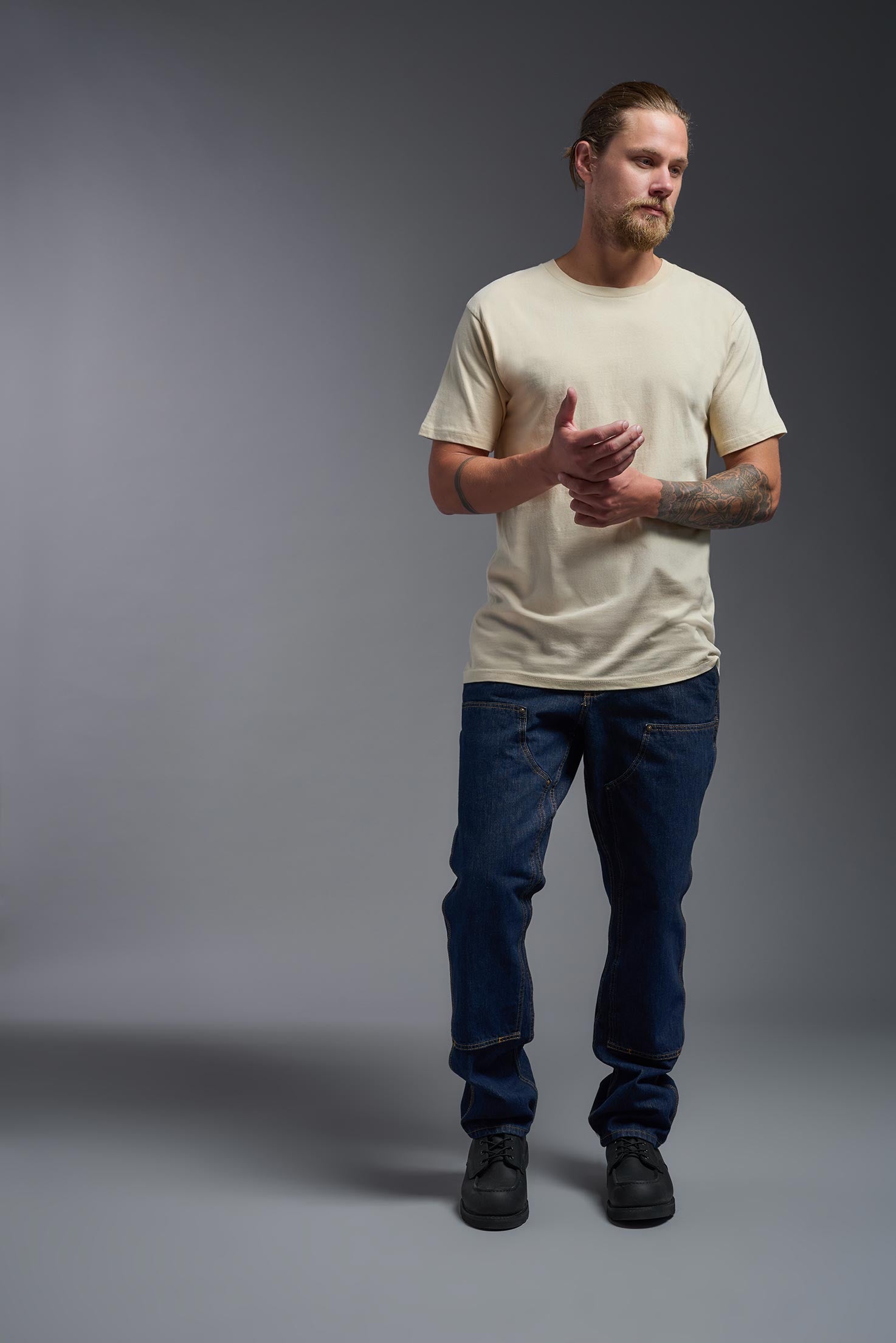 A male model wearing the unisex Americana Cotton Soft Tee in the color sand, made from 100% combed ring-spun USA-grown cotton, showing the classic fit from a front view. This premium shirt is Made in the USA. #sand