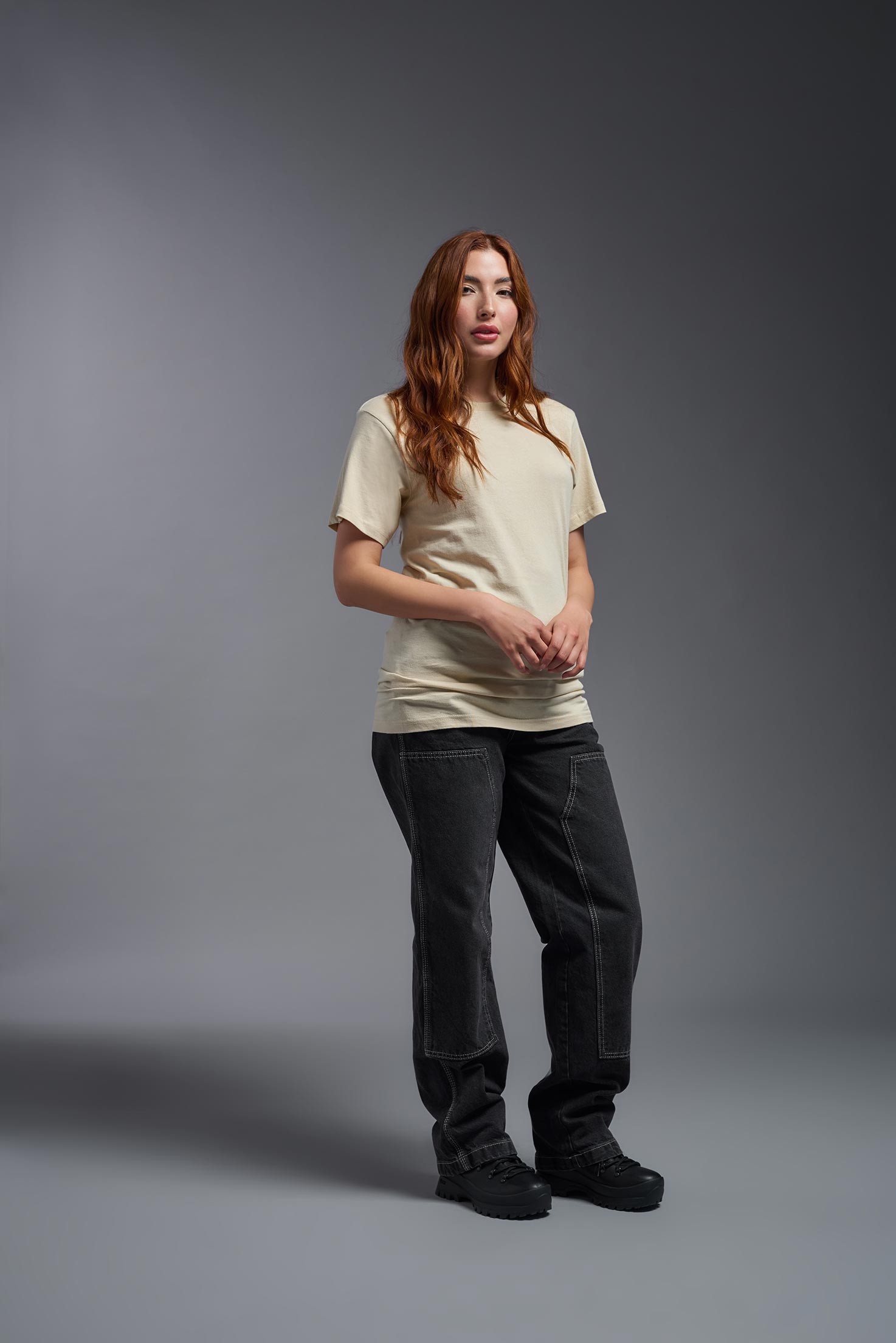 A female model wearing the unisex Americana Cotton Soft Tee in the color sand, made from 100% combed ring-spun USA-grown cotton, showing the classic fit from a front view. This premium shirt is Made in the USA. #sand