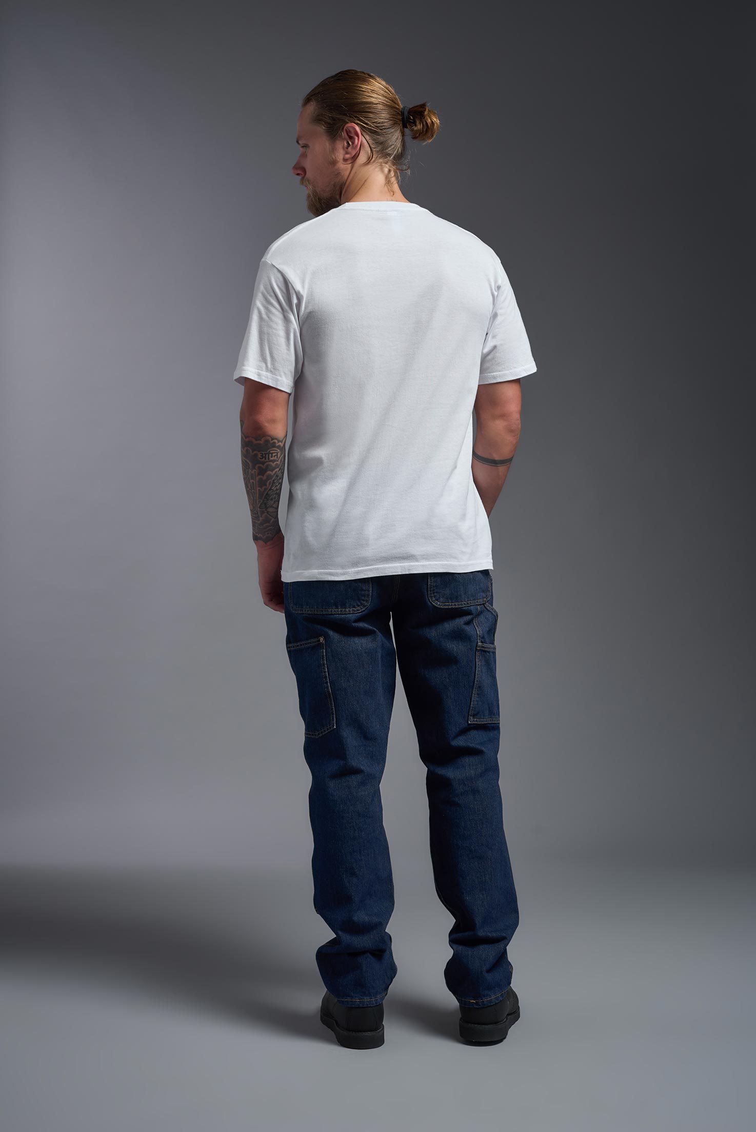 A male model wearing the unisex Americana Cotton Soft Tee in the color white, made from 100% combed ring-spun USA-grown cotton, showing the classic fit from a back view. This premium shirt is Made in the USA. #white