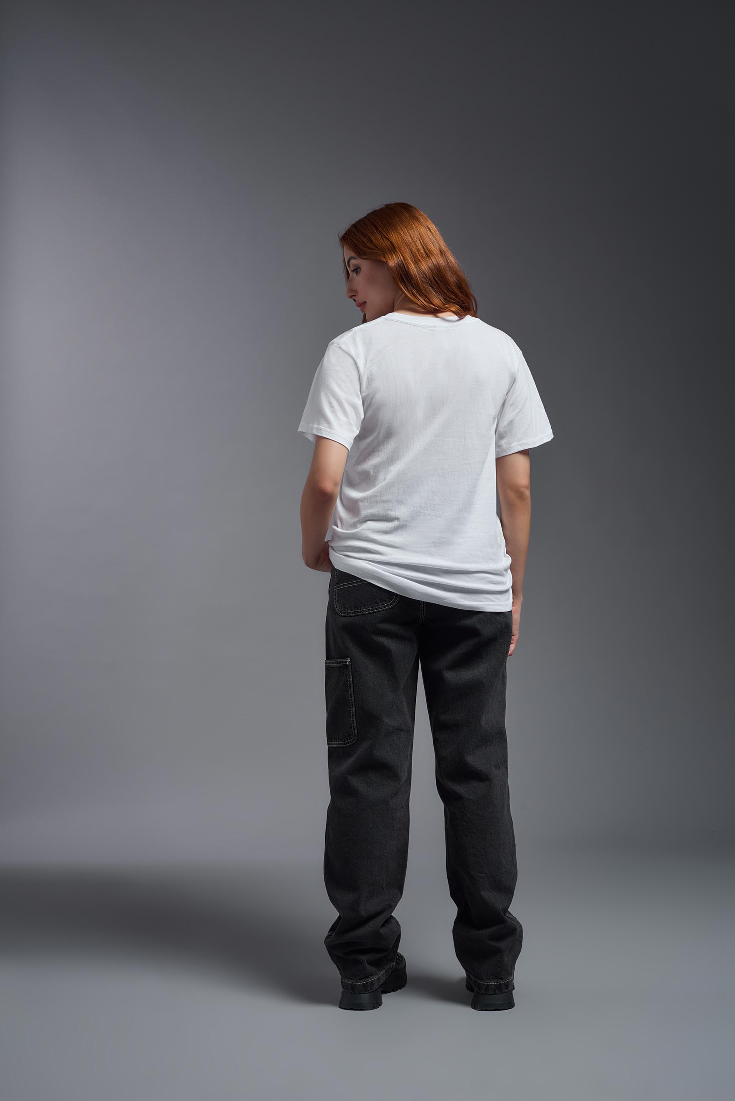 A female model wearing the unisex Americana Cotton Soft Tee in the color white, made from 100% combed ring-spun USA-grown cotton, showing the classic fit from a back view. This premium shirt is Made in the USA. #white