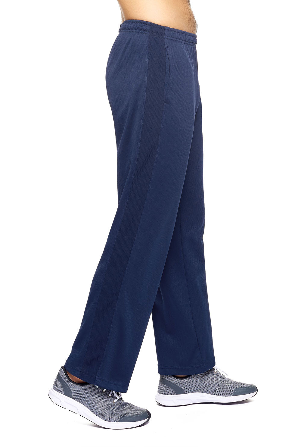 A male model on a white background wearing the men's Sphere City Sport Pants in the color navy made out of 100% polyester showing the relaxed fit from a side view. These pants quick-dry, wick moisture and are made in the USA. #navy
