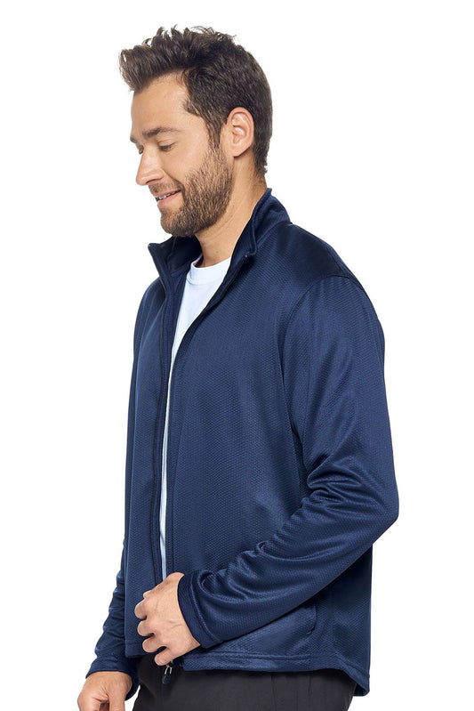 A male model on a white background wearing the men's Sphere Sportsman Jacket in the color navy made out of 100% polyester showing the relaxed fit from a side view. This jacket quick-dries, wicks moisture and is made in the USA. #navy