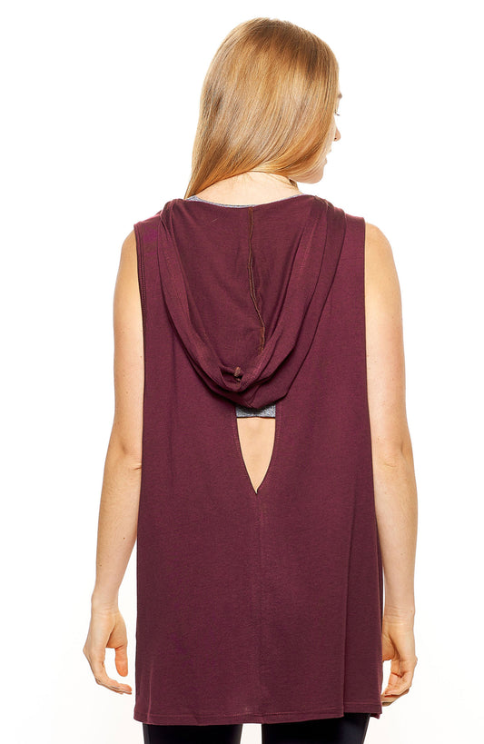A female model with braided hair wearing the women's MoCA Sleeveless Hoodie  in the color maroon, made from a luxurious blend of 50% LENZING Modal and 50% Combed Ring-Spun Cotton, showing the relaxed fit from a back view, hood down. This hoodie tank shirt is elevated, eco-friendly, made in the USA, and available for bulk purchase. #maroon