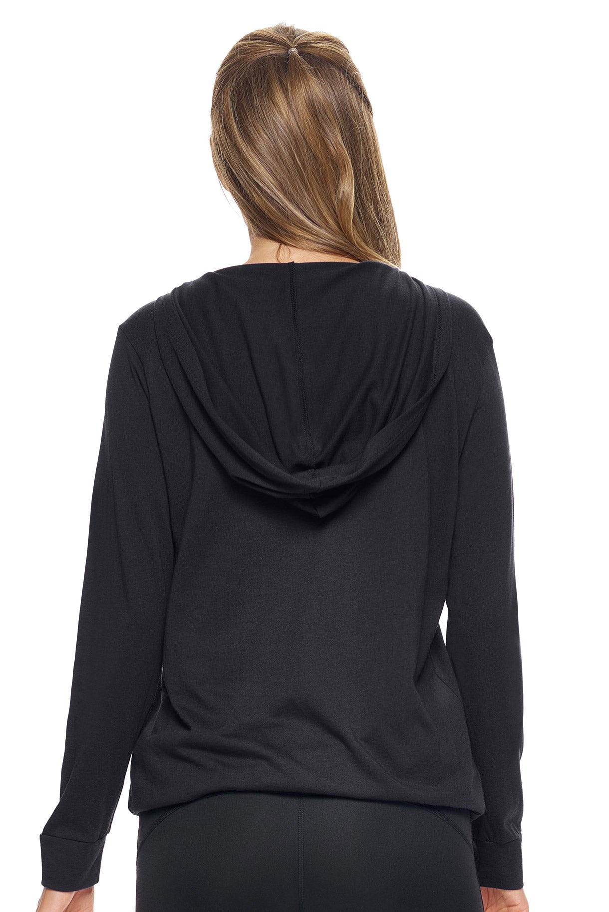 A female model with brown hair wearing the women's MoCA V-Neck Hoodie Shirt in the color black, made from a luxurious blend of 50% LENZING Modal and 50% Combed Ring-Spun Cotton, showing the relaxed fit from a back view. This fashion-forward, more sustainable t-shirt is elevated, eco-friendly, made in the USA, and available for bulk purchase. #black