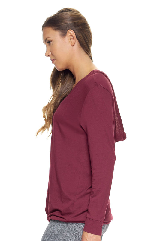 A female model with brown hair wearing the women's MoCA V-Neck Hoodie Shirt in the color maroon, made from a luxurious blend of 50% LENZING Modal and 50% Combed Ring-Spun Cotton, showing the relaxed fit from a side view. This fashion-forward, more sustainable t-shirt is elevated, eco-friendly, made in the USA, and available for bulk purchase. #maroon