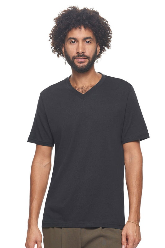 A male model with curly hair wearing the Men's MoCA V-Neck Tee in the color black, made from a luxurious blend of 50% LENZING Modal and 50% Combed Ring-Spun Cotton, showing the relaxed fit from a front view. This fashion-forward, more sustainable t-shirt is elevated, eco-friendly, made in the USA, and available for bulk purchase. #black