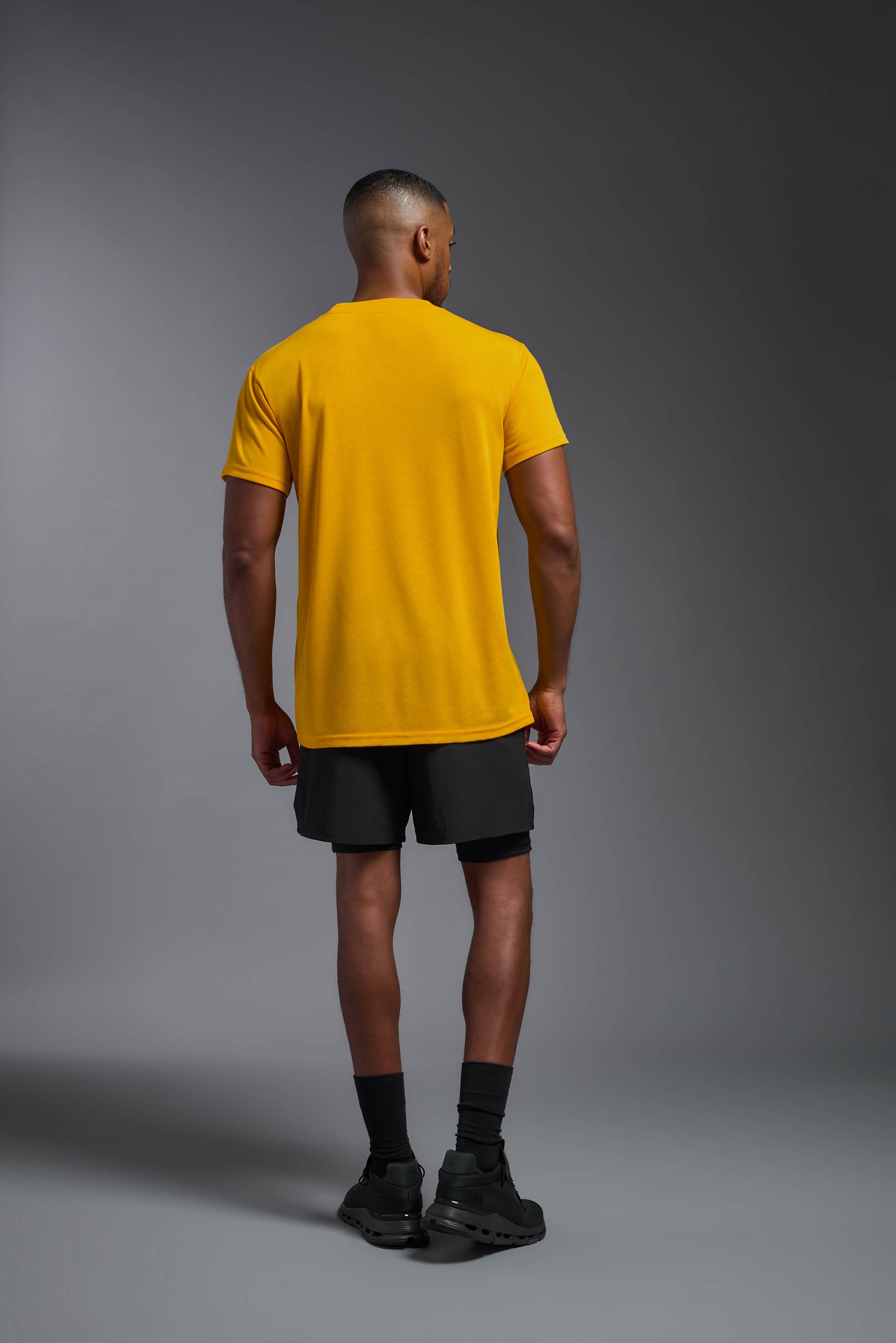 A male model wearing the men's DuroSoft Outdoor Tee in army yellow, made out of 100% filament polyester, showing the modern fit from a back view. This shirt quick-dries, wicks moisture and is made in the USA. #army-yellow