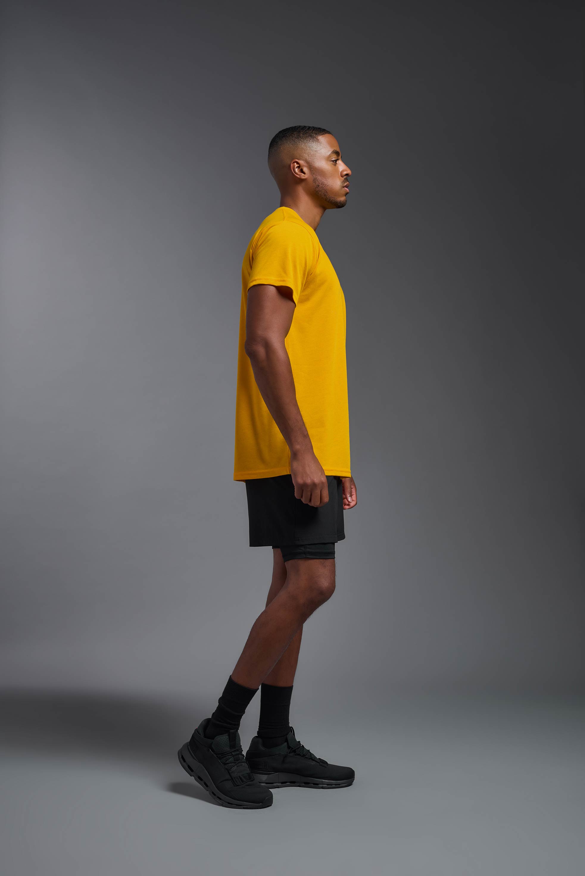 A male model wearing the men's DuroSoft Outdoor Tee in army yellow, made out of 100% filament polyester, showing the modern fit from a side view. This shirt quick-dries, wicks moisture and is made in the USA. #army-yellow