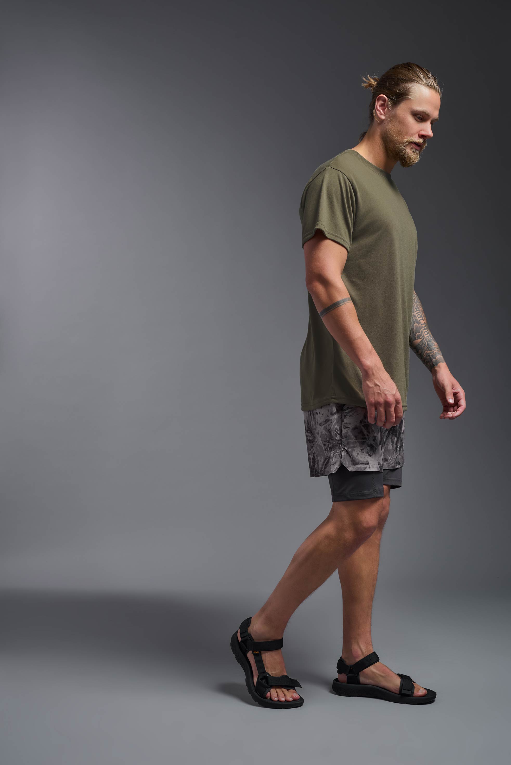 A male model wearing the men's DuroSoft Outdoor Tee in the color tan 499, made out of 100% filament polyester, showing the modern fit from a side view. This shirt quick-dries, wicks moisture and is made in the USA. #tan-499