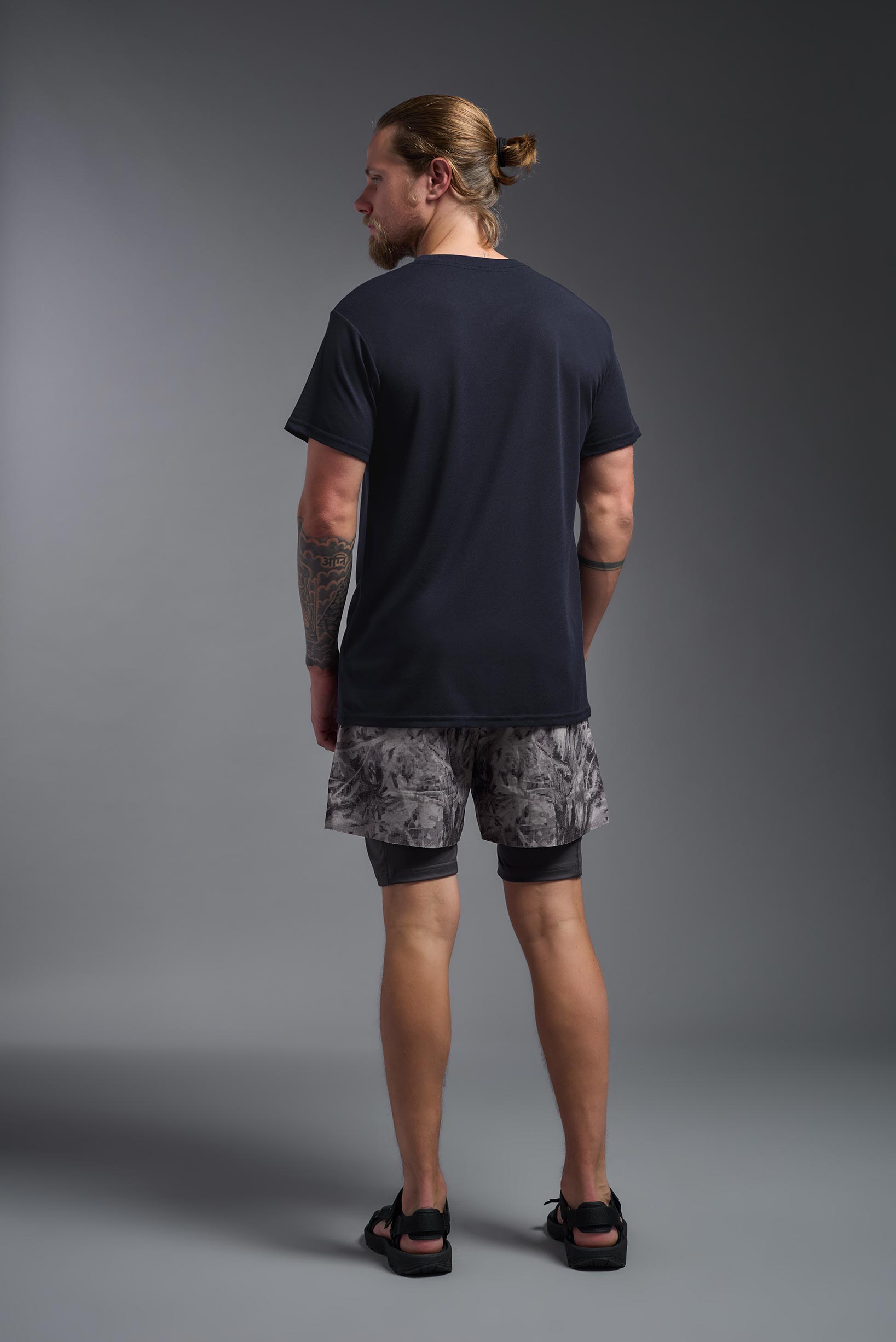 A male model wearing the men's DuroSoft Outdoor Tee in the color army blue, made out of 100% filament polyester, showing the modern fit from a back view. This shirt quick-dries, wicks moisture and is made in the USA. #army-blue