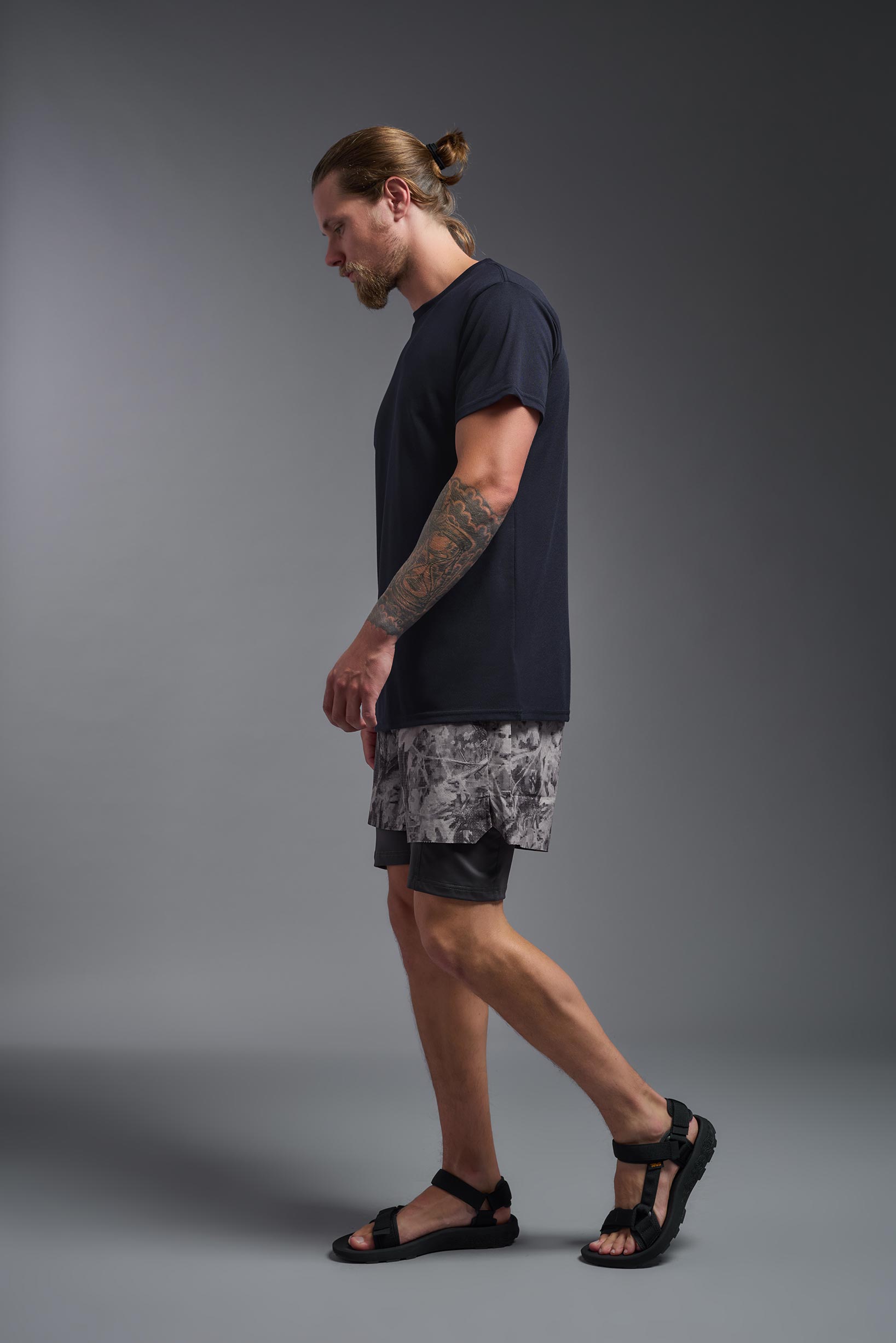 A male model wearing the men's DuroSoft Outdoor Tee in the color army blue, made out of 100% filament polyester, showing the modern fit from a side view. This shirt quick-dries, wicks moisture and is made in the USA. #army-blue