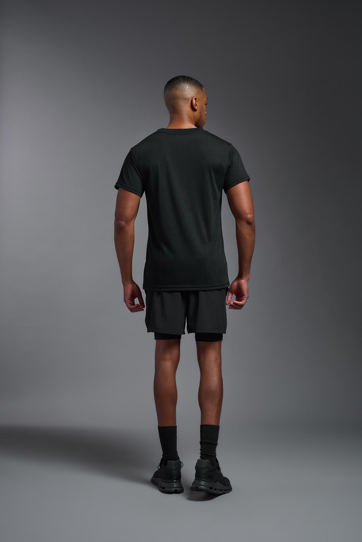 A male model wearing the men's DuroSoft Outdoor Tee in black, made out of 100% filament polyester, showing the modern fit from a back view. This shirt quick-dries, wicks moisture and is made in the USA. #black