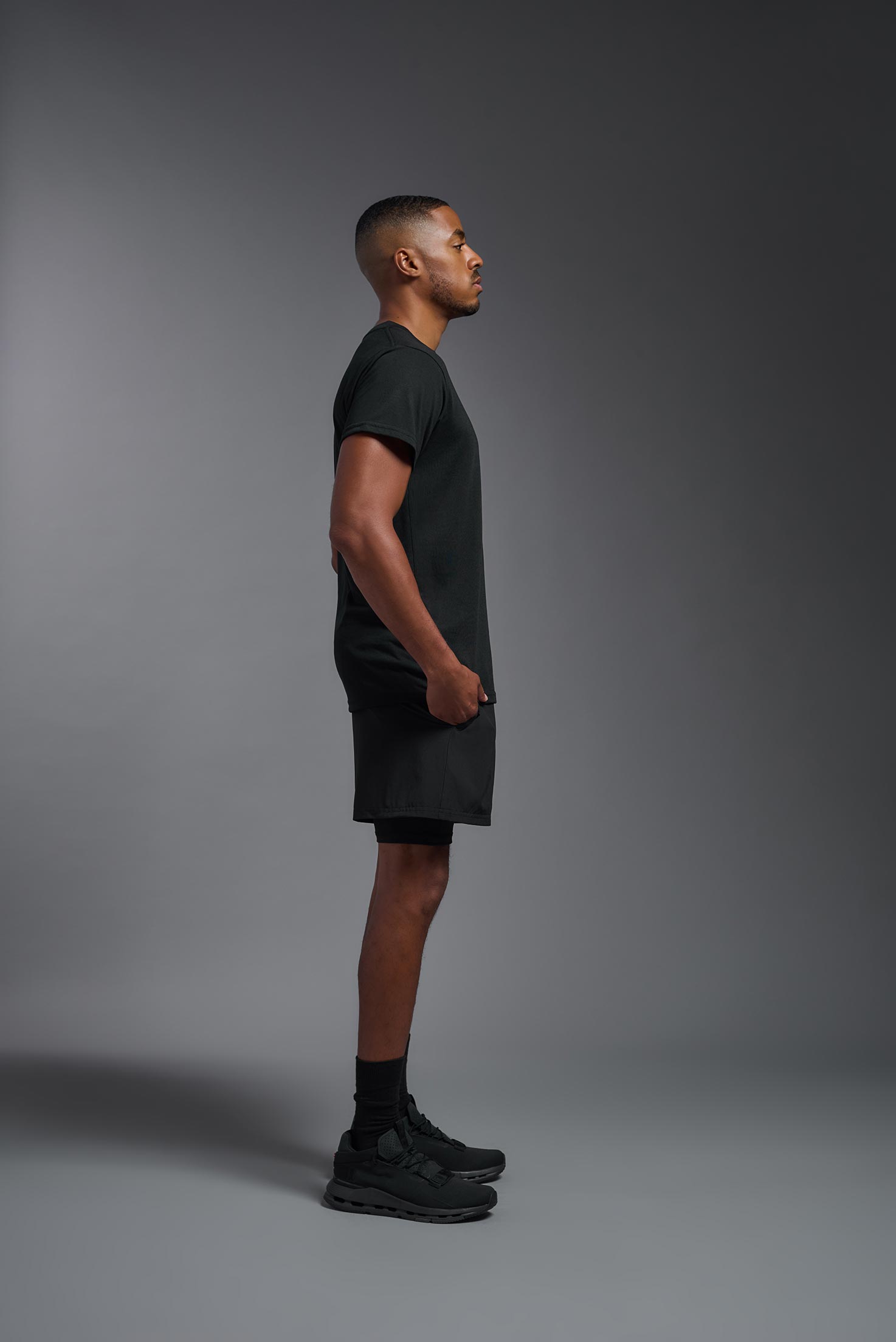 A male model wearing the men's DuroSoft Outdoor Tee in black, made out of 100% filament polyester, showing the modern fit from a side view. This shirt quick-dries, wicks moisture and is made in the USA. #black