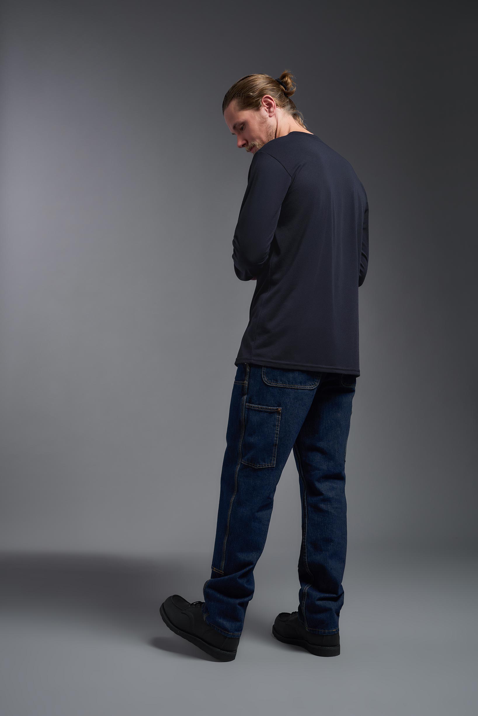 A male model wearing the men's DuroSoft Outdoor Long Sleeve in the color army blue, made out of 100% filament polyester, showing the modern fit from a back view. This shirt quick-dries, wicks moisture and is made in the USA. #army-blue