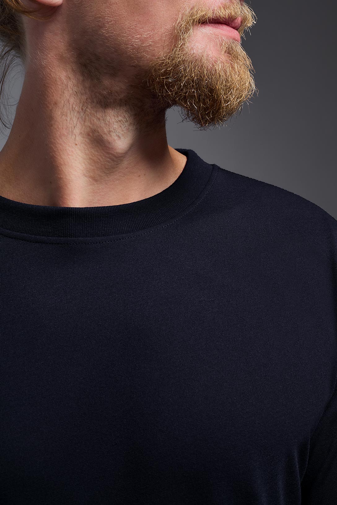 A male model wearing the men's DuroSoft Outdoor Long Sleeve in the color army blue, made out of 100% filament polyester, showing the modern fit from a collar closeup view. This shirt quick-dries, wicks moisture and is made in the USA. #army-blue