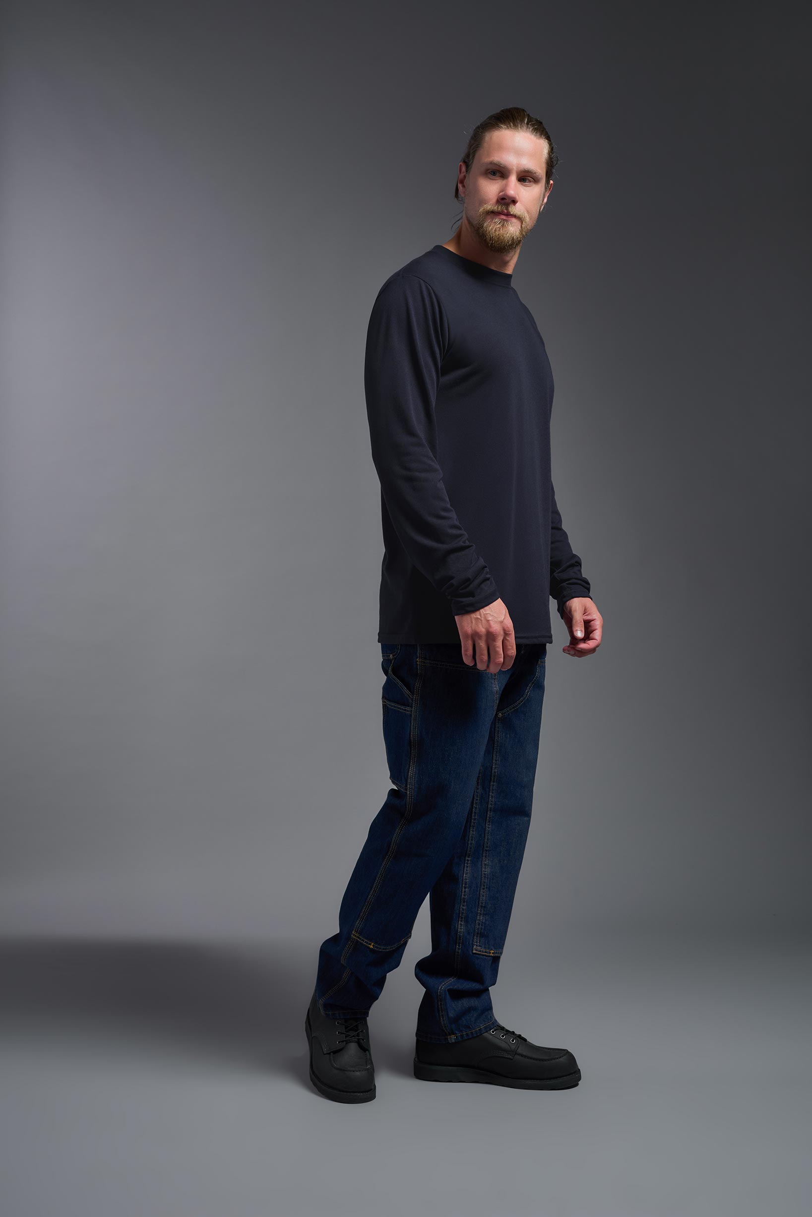 A male model wearing the men's DuroSoft Outdoor Long Sleeve in the color army blue, made out of 100% filament polyester, showing the modern fit from a side view. This shirt quick-dries, wicks moisture and is made in the USA. #army-blue