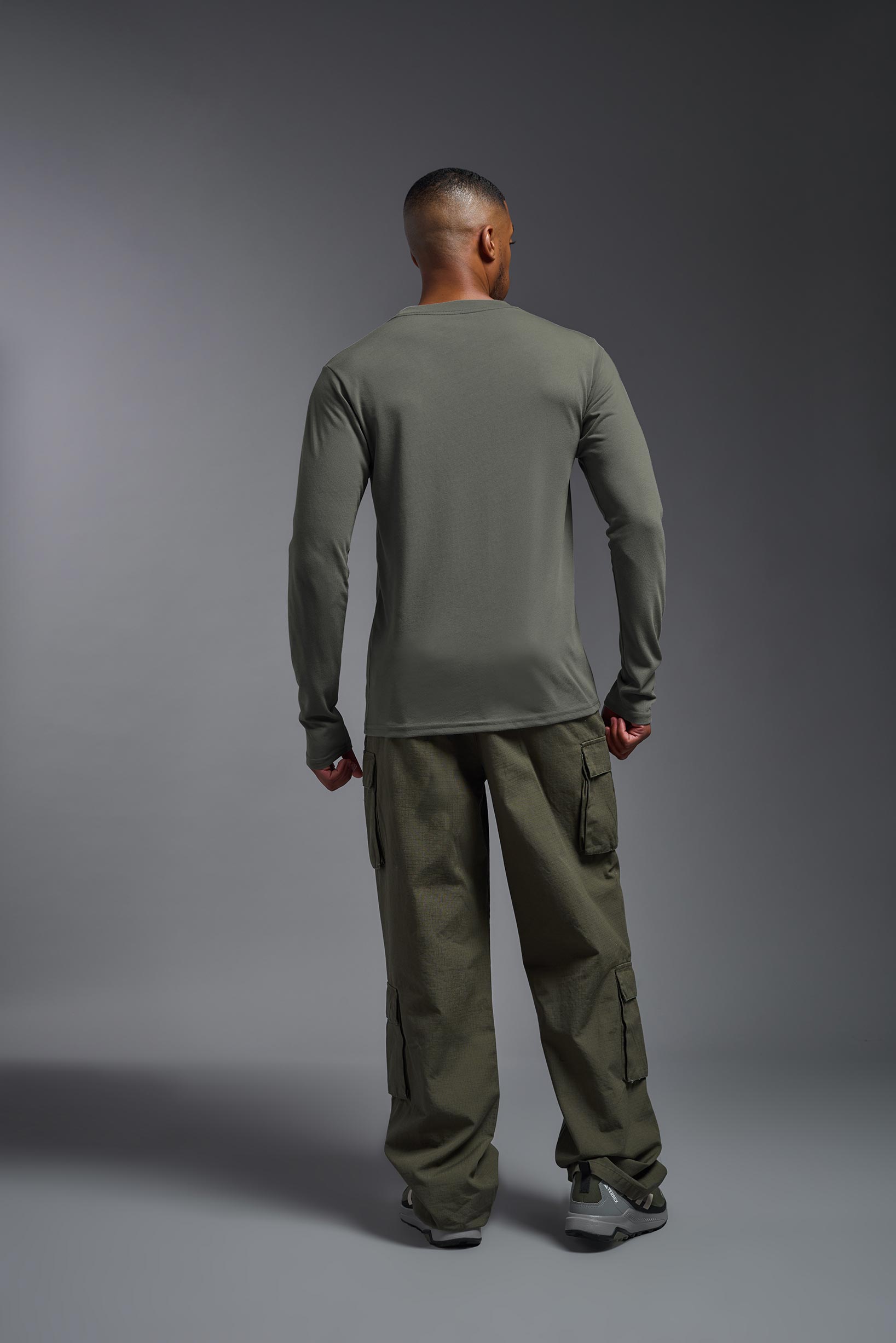 A male model wearing the men's DuroSoft Outdoor Long Sleeve in the color army gray made out of 100% filament polyester, showing the modern fit from a back view. This shirt quick-dries, wicks moisture and is made in the USA. #army-gray