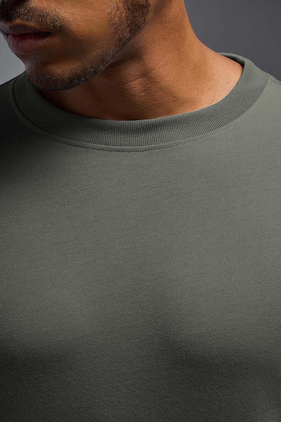 A male model wearing the men's DuroSoft Outdoor Long Sleeve in the color army gray made out of 100% filament polyester, showing the modern fit from a collar closeup view. This shirt quick-dries, wicks moisture and is made in the USA. #army-gray