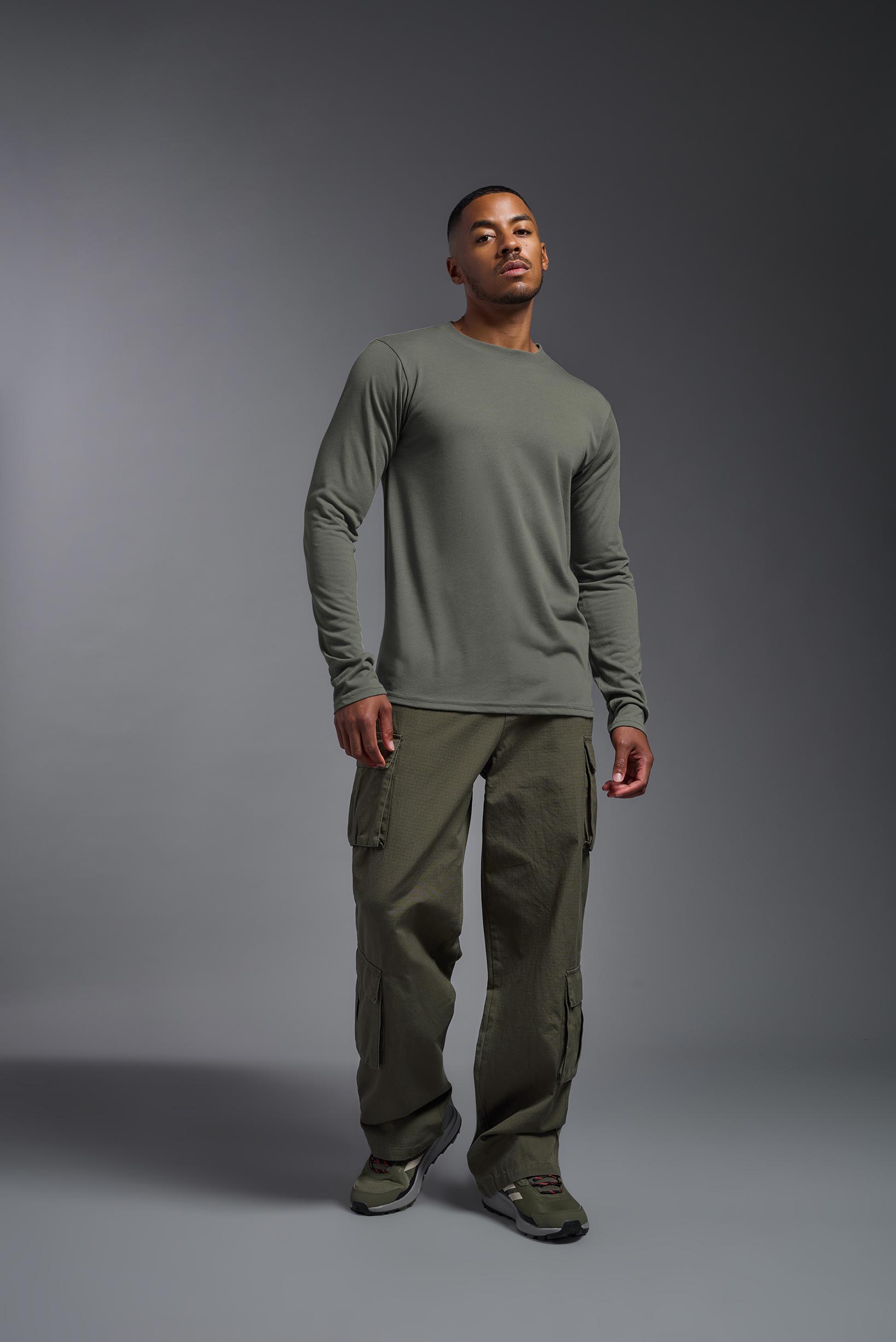 A male model wearing the men's DuroSoft Outdoor Long Sleeve in the color army gray made out of 100% filament polyester, showing the modern fit from a front view. This shirt quick-dries, wicks moisture and is made in the USA. #army-gray