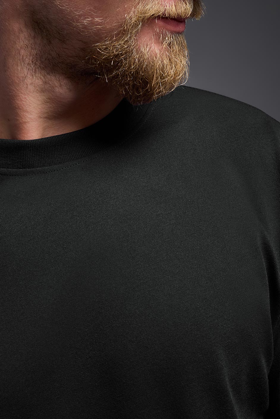 A male model wearing the men's DuroSoft Outdoor Long Sleeve in the color black, made out of 100% filament polyester, showing the modern fit from a closeup collar front view. This shirt quick-dries, wicks moisture and is made in the USA. #black