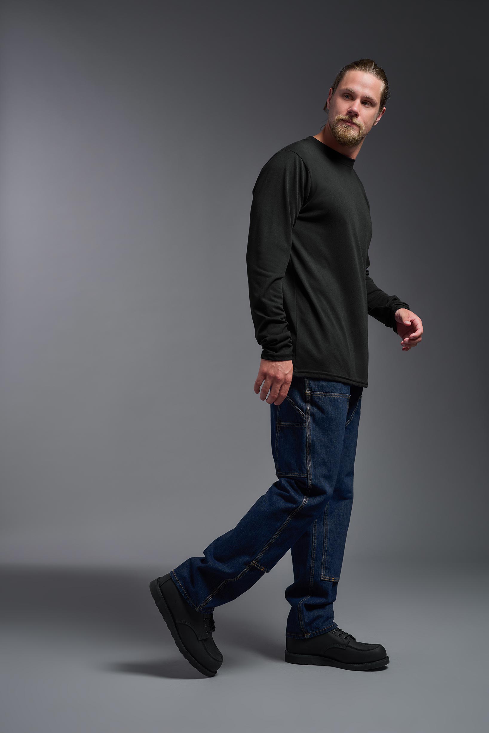 A male model wearing the men's DuroSoft Outdoor Long Sleeve in the color black, made out of 100% filament polyester, showing the modern fit from a side view. This shirt quick-dries, wicks moisture and is made in the USA. #black
