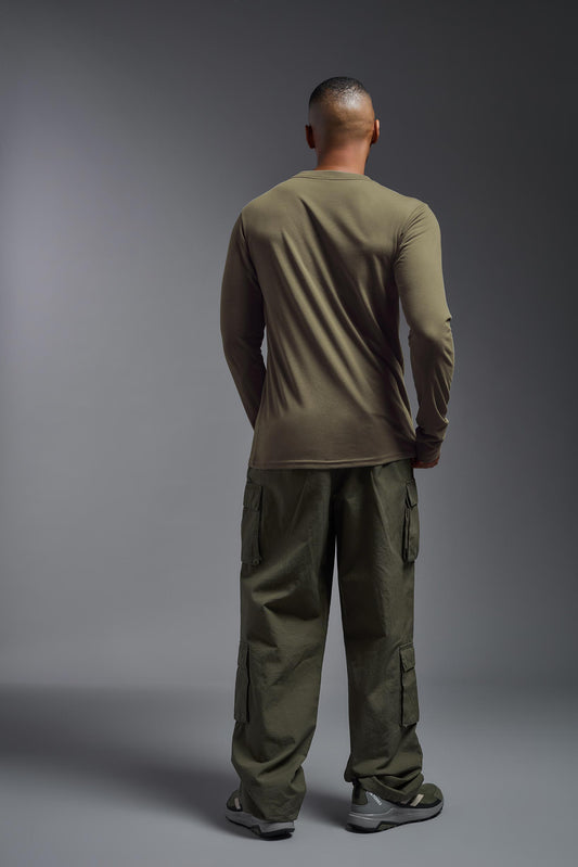 A male model wearing the men's DuroSoft Outdoor Long Sleeve in the color tan-499 made out of 100% filament polyester, showing the modern fit from a back view. This shirt quick-dries, wicks moisture and is made in the USA. #tan-499