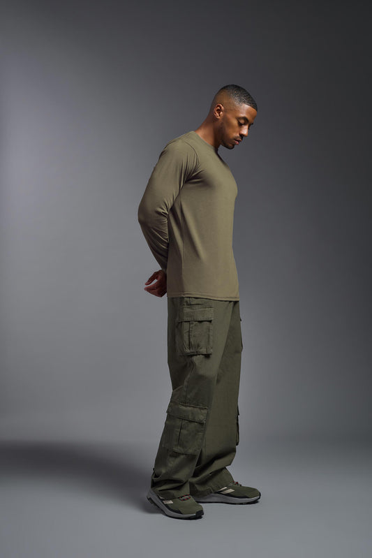 A male model wearing the men's DuroSoft Outdoor Long Sleeve in the color tan-499 made out of 100% filament polyester, showing the modern fit from a side view. This shirt quick-dries, wicks moisture and is made in the USA. #tan-499