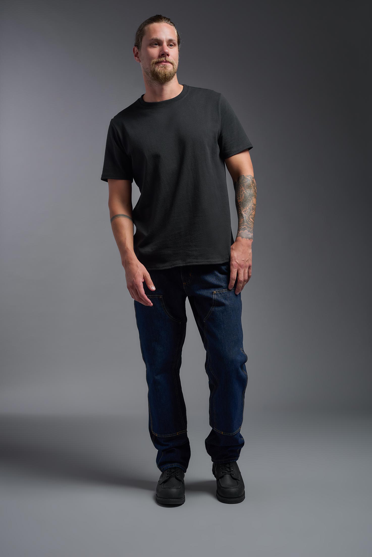 A male model wearing the unisex Imagen Short Sleeve Crewneck T-Shirt in the color black, made from 50% U.S. Grown Regenerative Cotton and 50% Recycled Polyester, showing the Relaxed Fit from a front view. This sustainable shirt is Made in the USA. #black