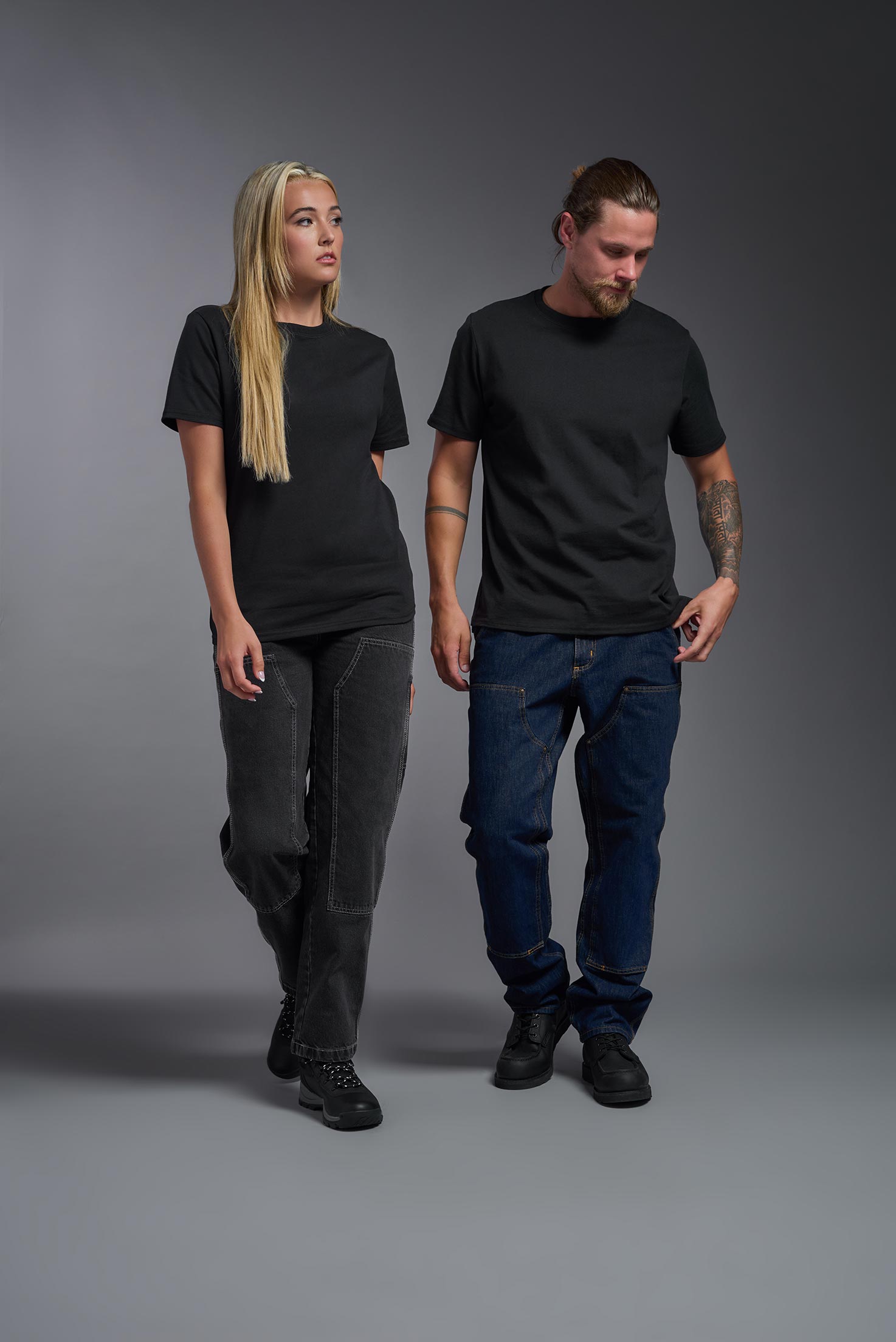 A male and female model wearing the unisex Imagen Short Sleeve Crewneck T-Shirt in the color black, made from 50% U.S. Grown Regenerative Cotton and 50% Recycled Polyester, showing the Relaxed Fit from a front view. This sustainable shirt is Made in the USA. #black