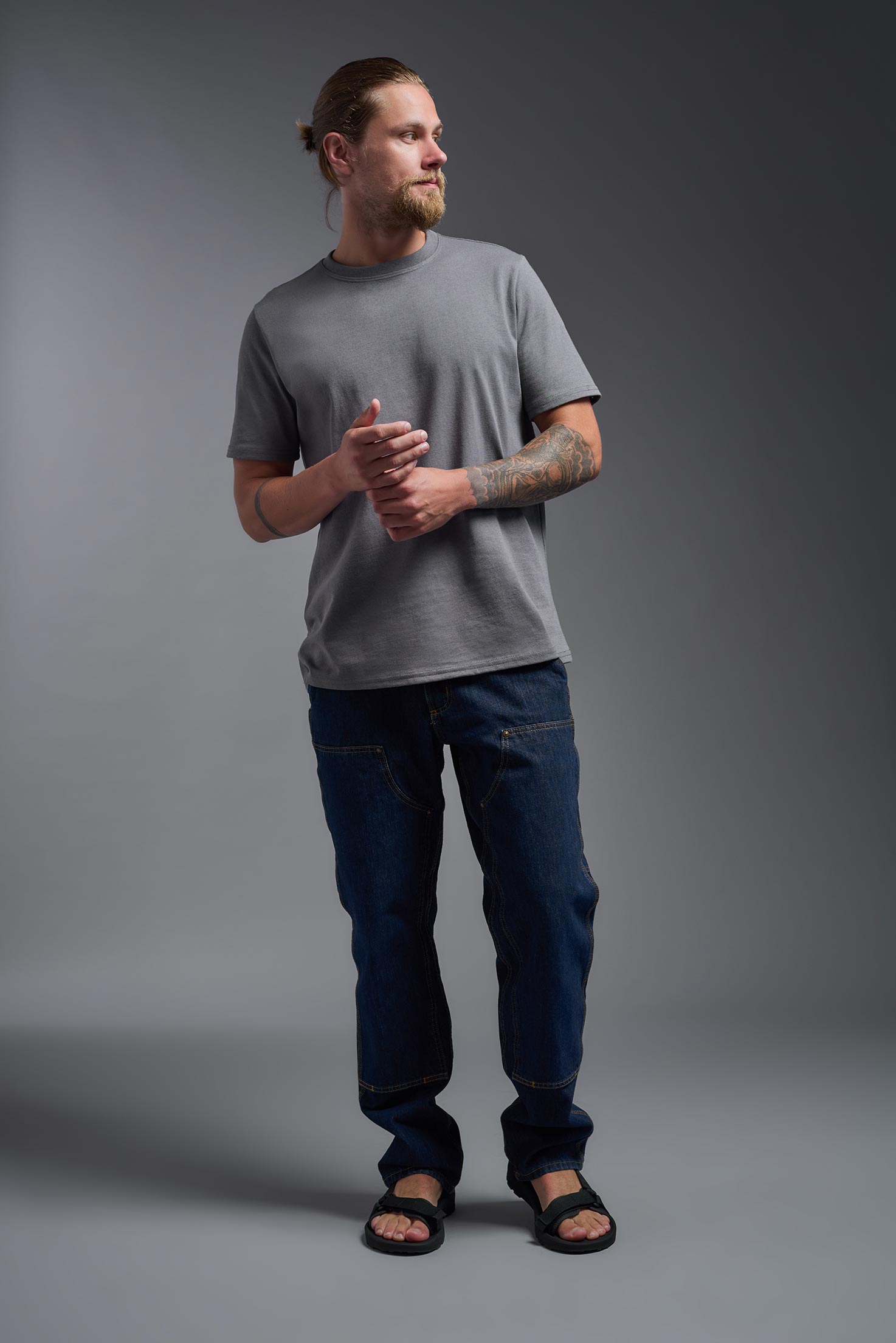 A male model wearing the unisex Imagen Short Sleeve Crewneck T-Shirt in the color carbon, made from 50% U.S. Grown Regenerative Cotton and 50% Recycled Polyester, showing the Relaxed Fit from a front view. This sustainable shirt is Made in the USA. #carbon