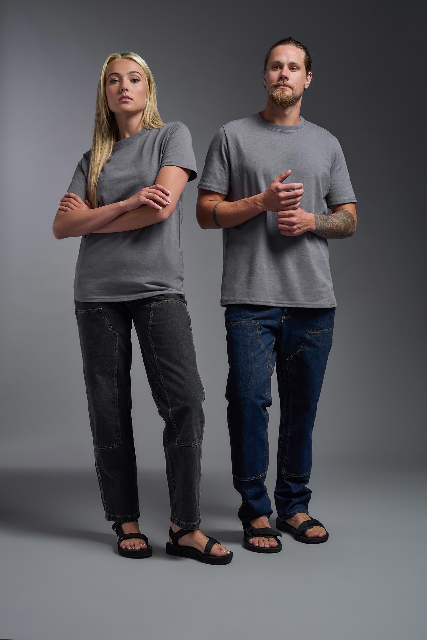 A male and female model wearing the unisex Imagen Short Sleeve Crewneck T-Shirt in the color carbon, made from 50% U.S. Grown Regenerative Cotton and 50% Recycled Polyester, showing the Relaxed Fit from a front view. This sustainable shirt is Made in the USA. #carbon