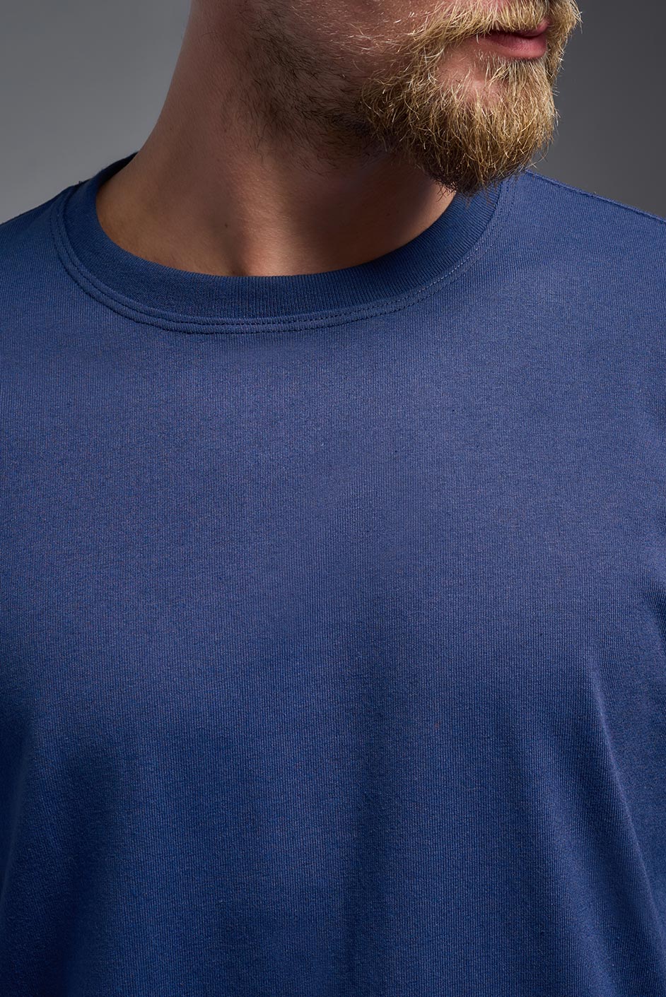 A female model wearing the unisex Imagen Short Sleeve Crewneck T-Shirt in the color navy, made from 50% U.S. Grown Regenerative Cotton and 50% Recycled Polyester, showing the Relaxed Fit from a close-up collar view. This sustainable shirt is Made in the USA. #navy