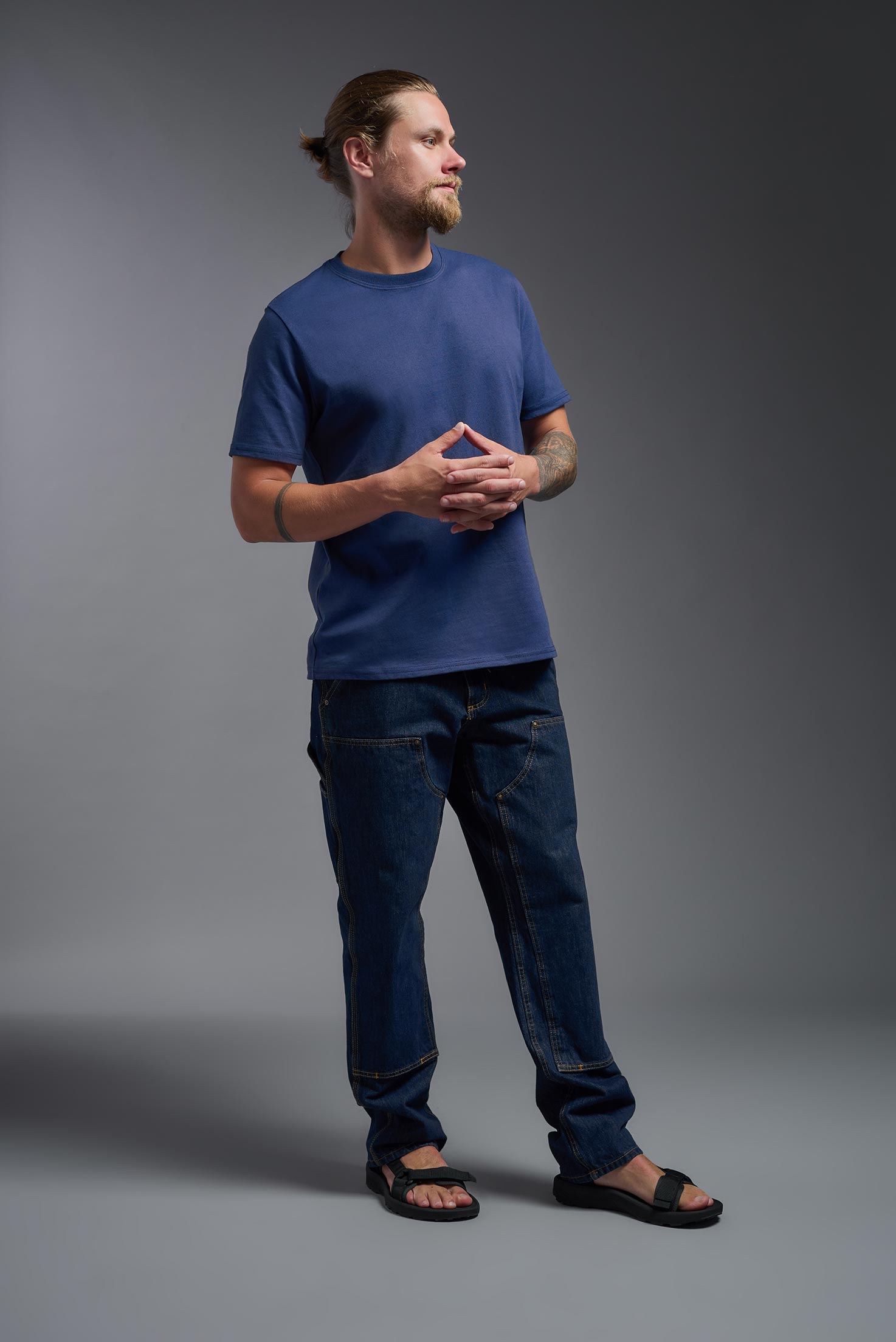 A male model wearing the unisex Imagen Short Sleeve Crewneck T-Shirt in the color navy, made from 50% U.S. Grown Regenerative Cotton and 50% Recycled Polyester, showing the Relaxed Fit from a front view. This sustainable shirt is Made in the USA. #navy