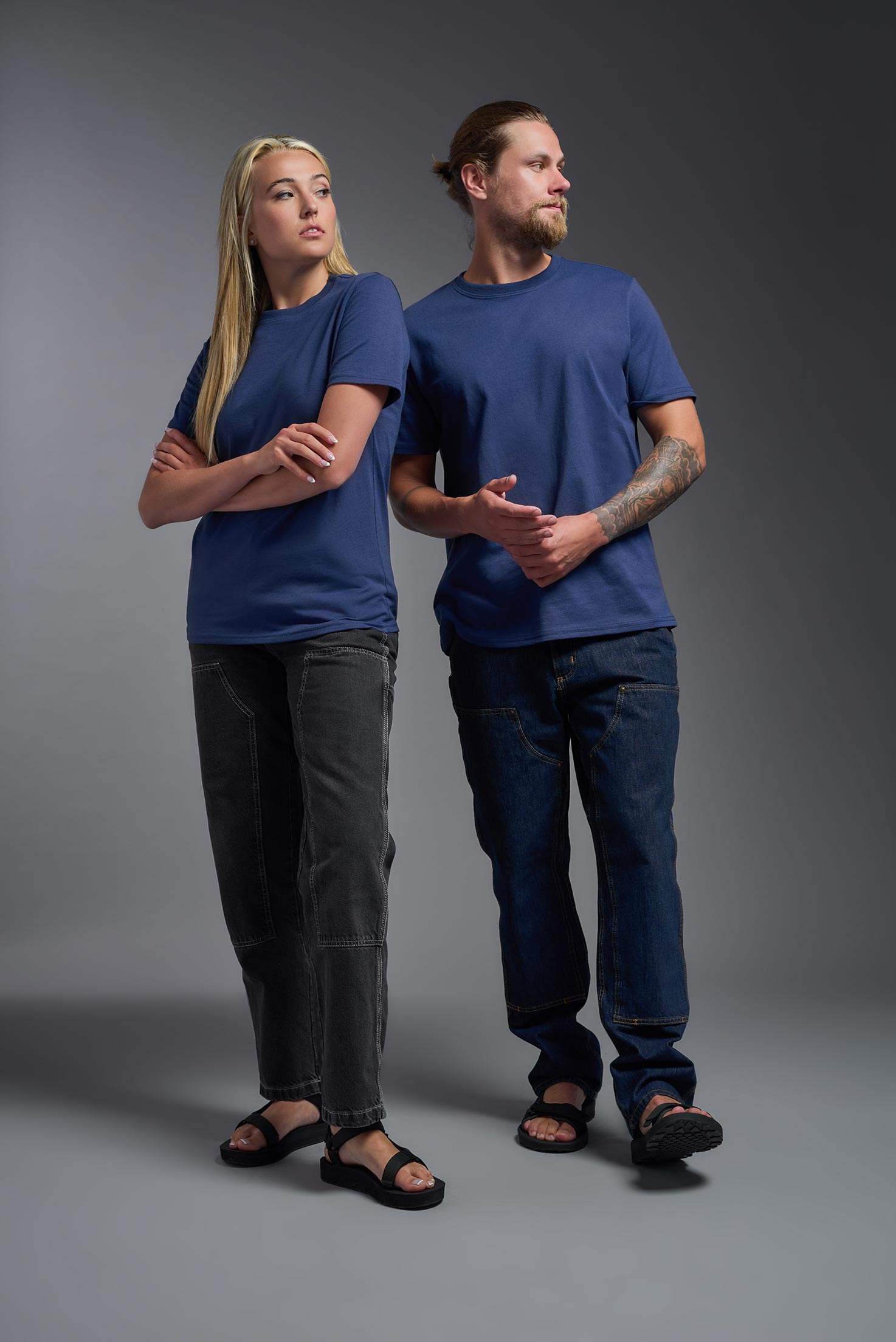 A male and female model wearing the unisex Imagen Short Sleeve Crewneck T-Shirt in the color navy, made from 50% U.S. Grown Regenerative Cotton and 50% Recycled Polyester, showing the Relaxed Fit from a front view. This sustainable shirt is Made in the USA. #navy