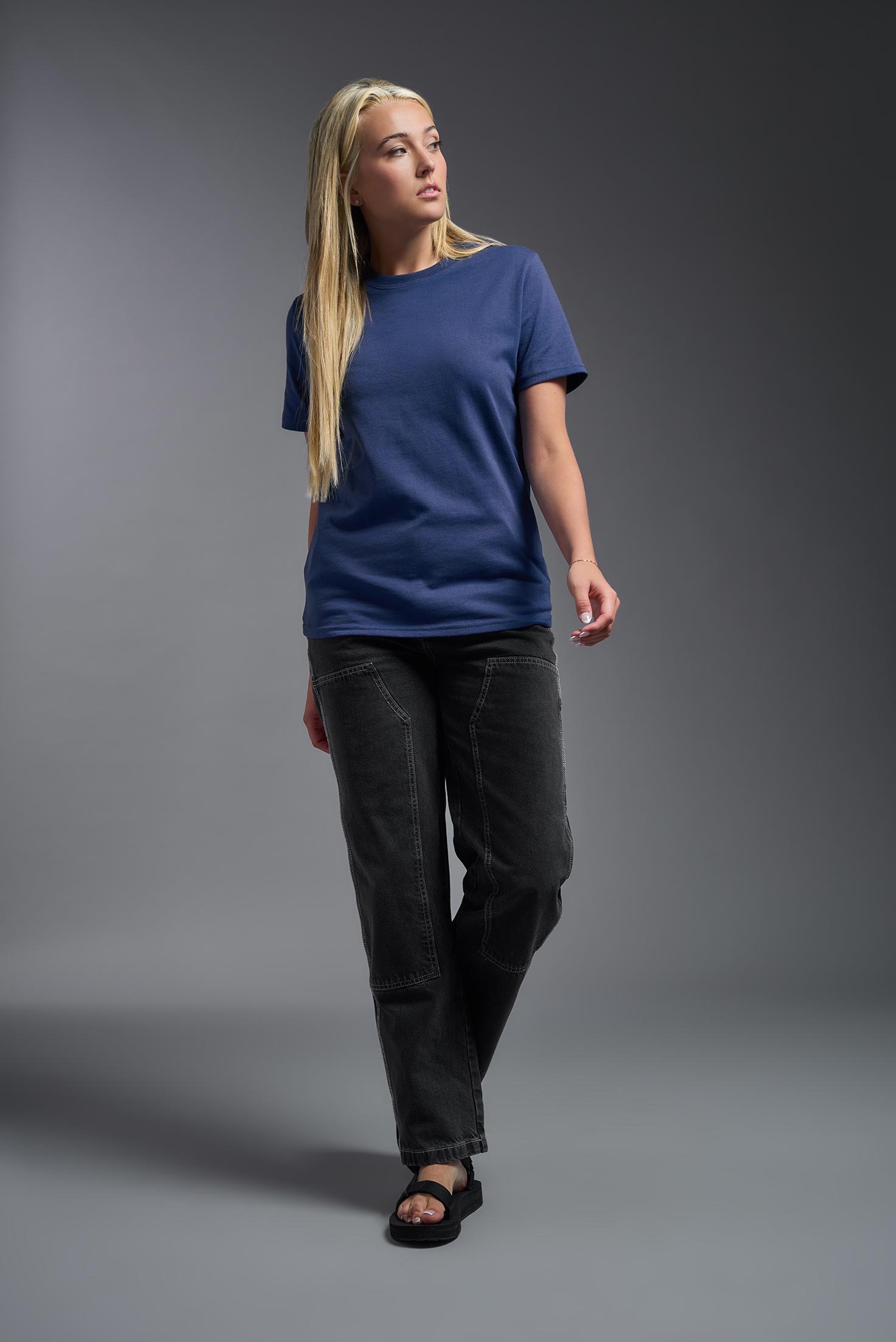 A female model wearing the unisex Imagen Short Sleeve Crewneck T-Shirt in the color navy, made from 50% U.S. Grown Regenerative Cotton and 50% Recycled Polyester, showing the Relaxed Fit from a front view. This sustainable shirt is Made in the USA. #navy