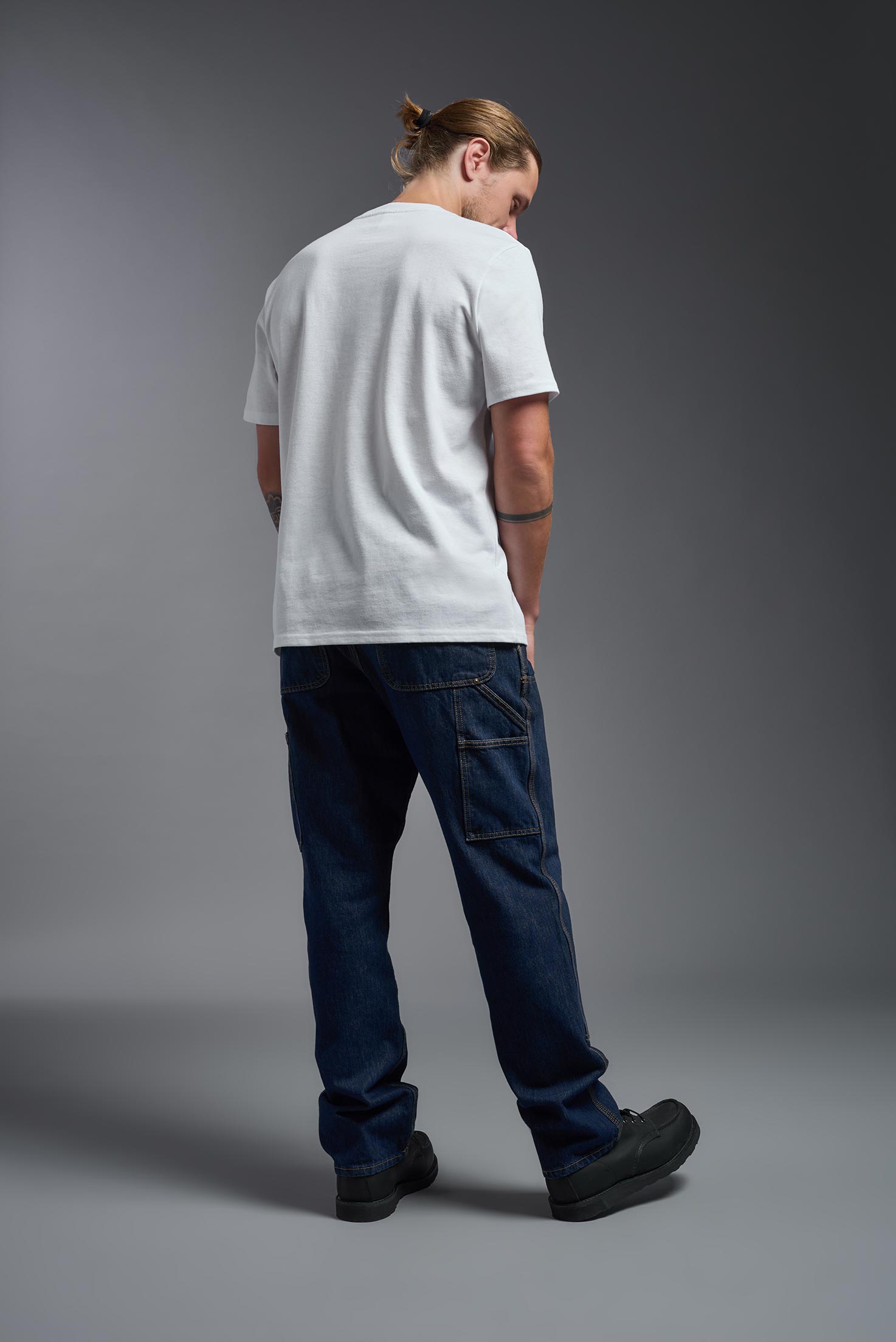 A male model wearing the unisex Imagen Short Sleeve Crewneck T-Shirt in the color white, made from 50% U.S. Grown Regenerative Cotton and 50% Recycled Polyester, showing the Relaxed Fit from a back view. This sustainable shirt is Made in the USA. #white
