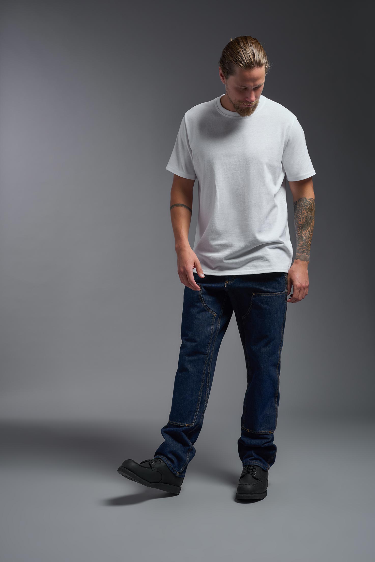 A male model wearing the unisex Imagen Short Sleeve Crewneck T-Shirt in the color white, made from 50% U.S. Grown Regenerative Cotton and 50% Recycled Polyester, showing the Relaxed Fit from a front view. This sustainable shirt is Made in the USA. #white