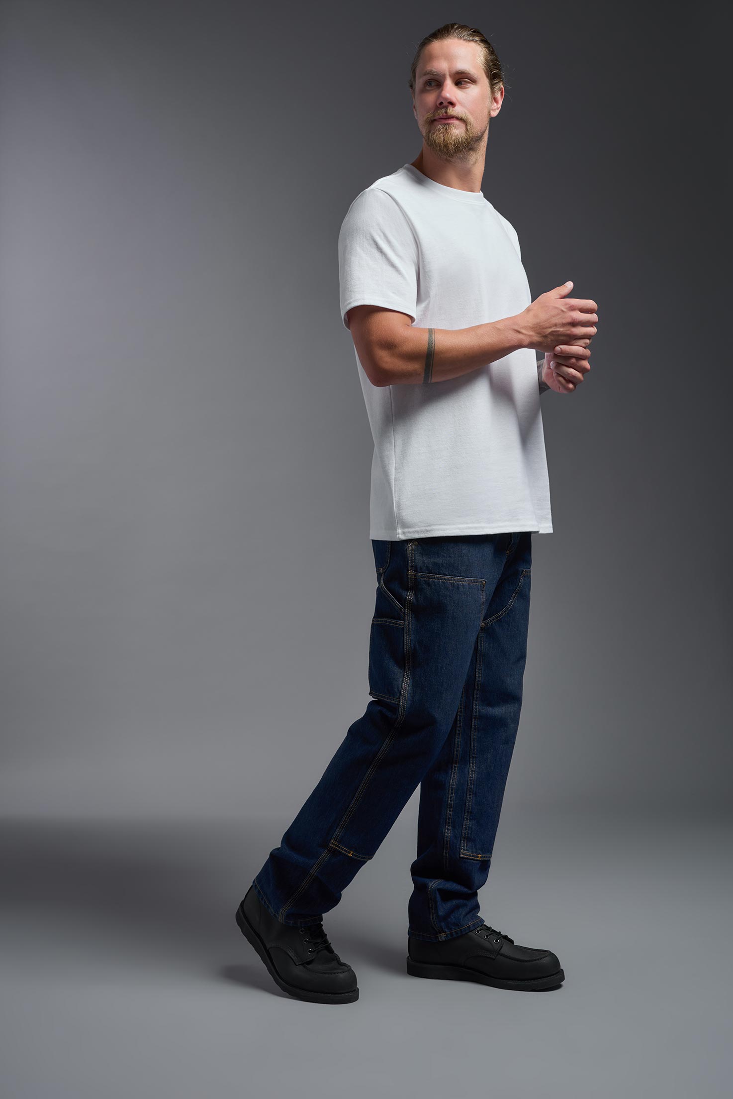 A male model wearing the unisex Imagen Short Sleeve Crewneck T-Shirt in the color white, made from 50% U.S. Grown Regenerative Cotton and 50% Recycled Polyester, showing the Relaxed Fit from a side view. This sustainable shirt is Made in the USA. #white