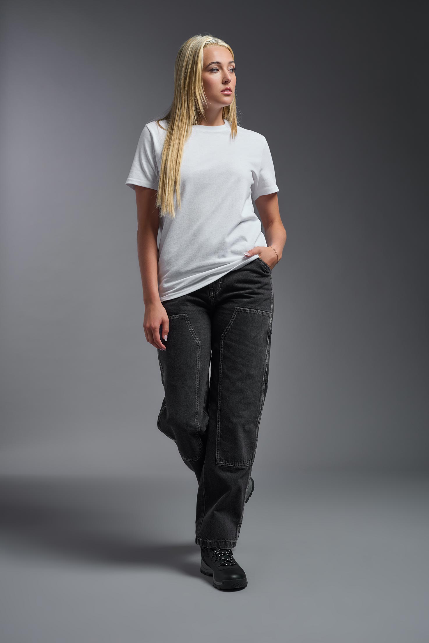 A female model wearing the unisex Imagen Short Sleeve Crewneck T-Shirt in the color white, made from 50% U.S. Grown Regenerative Cotton and 50% Recycled Polyester, showing the Relaxed Fit from a front view. This sustainable shirt is Made in the USA. #white