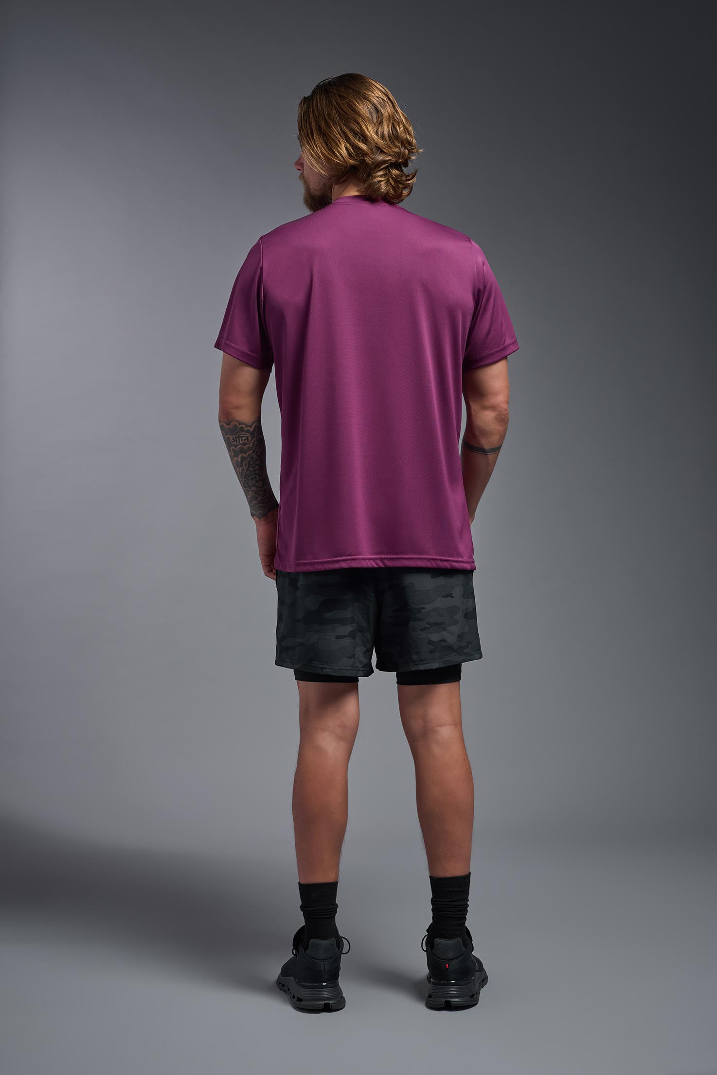 A male model wearing the men's EcoTek™ Recycled Performance Tee in the color merlot, made out of 100% recycled polyester REPREVE®, showing the modern fit from a back view. This shirt features a mechanical stretch, quick-dries, wicks moisture and is made in the USA. #merlot