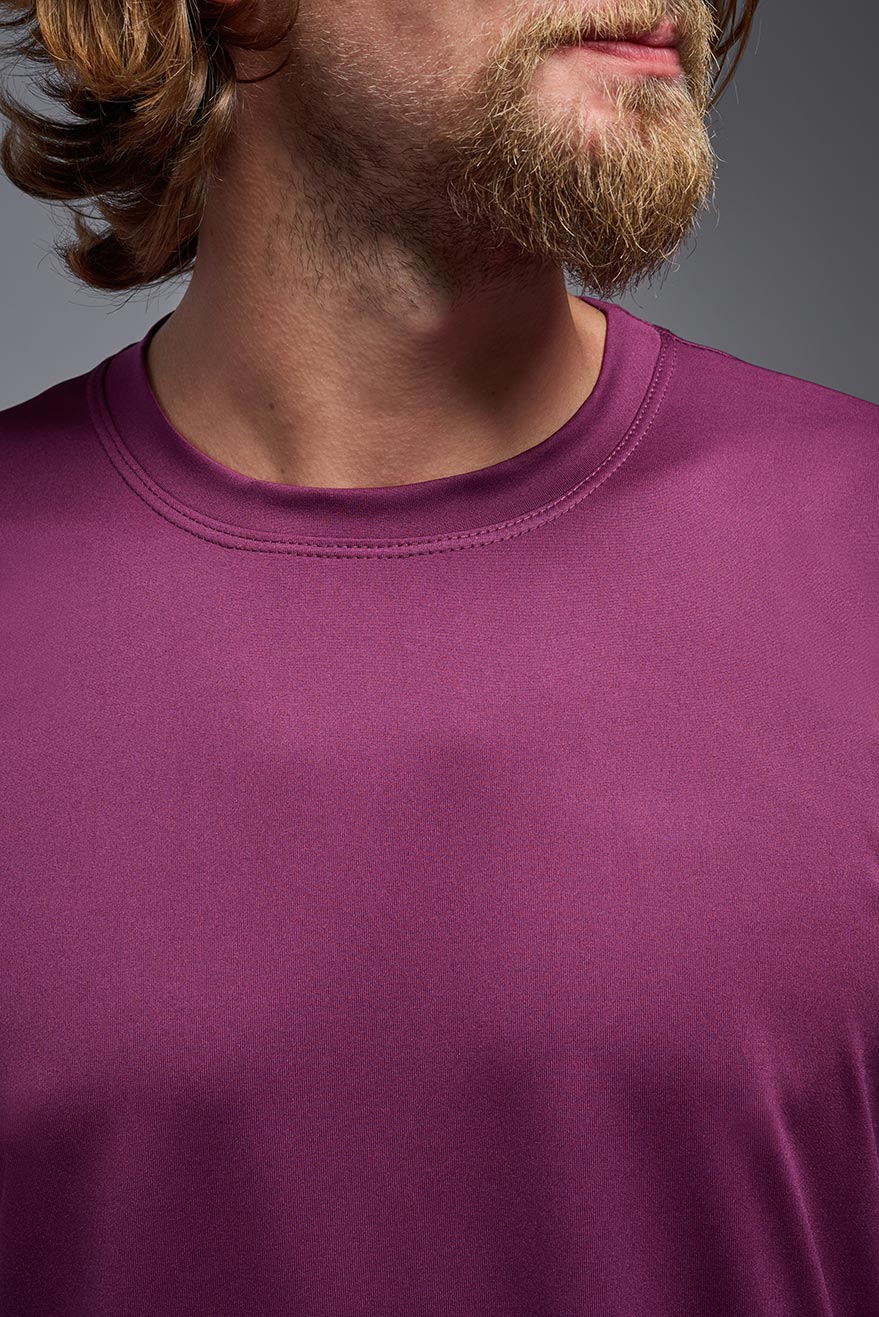 A male model wearing the men's EcoTek™ Recycled Performance Tee in the color merlot, made out of 100% recycled polyester REPREVE®, showing the modern fit from a collar view close-up. This shirt features a mechanical stretch, quick-dries, wicks moisture and is made in the USA. #merlot