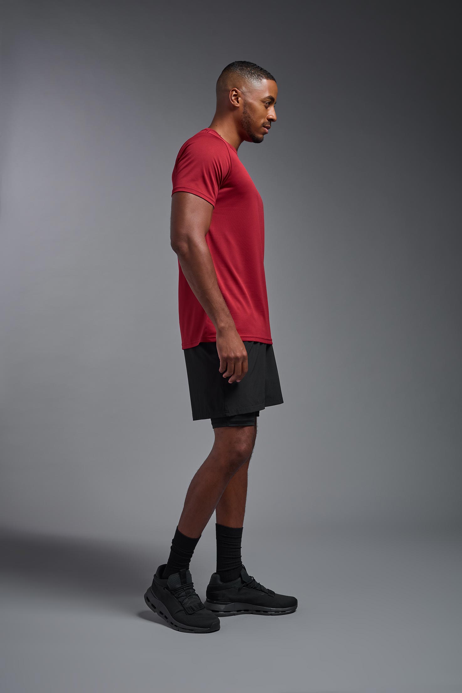 A male model wearing the men's EcoTek™ Recycled Performance Tee in the color poinsettia, made out of 100% recycled polyester REPREVE®, showing the modern fit from a side view. This shirt features a mechanical stretch, quick-dries, wicks moisture and is made in the USA. #poinsettia