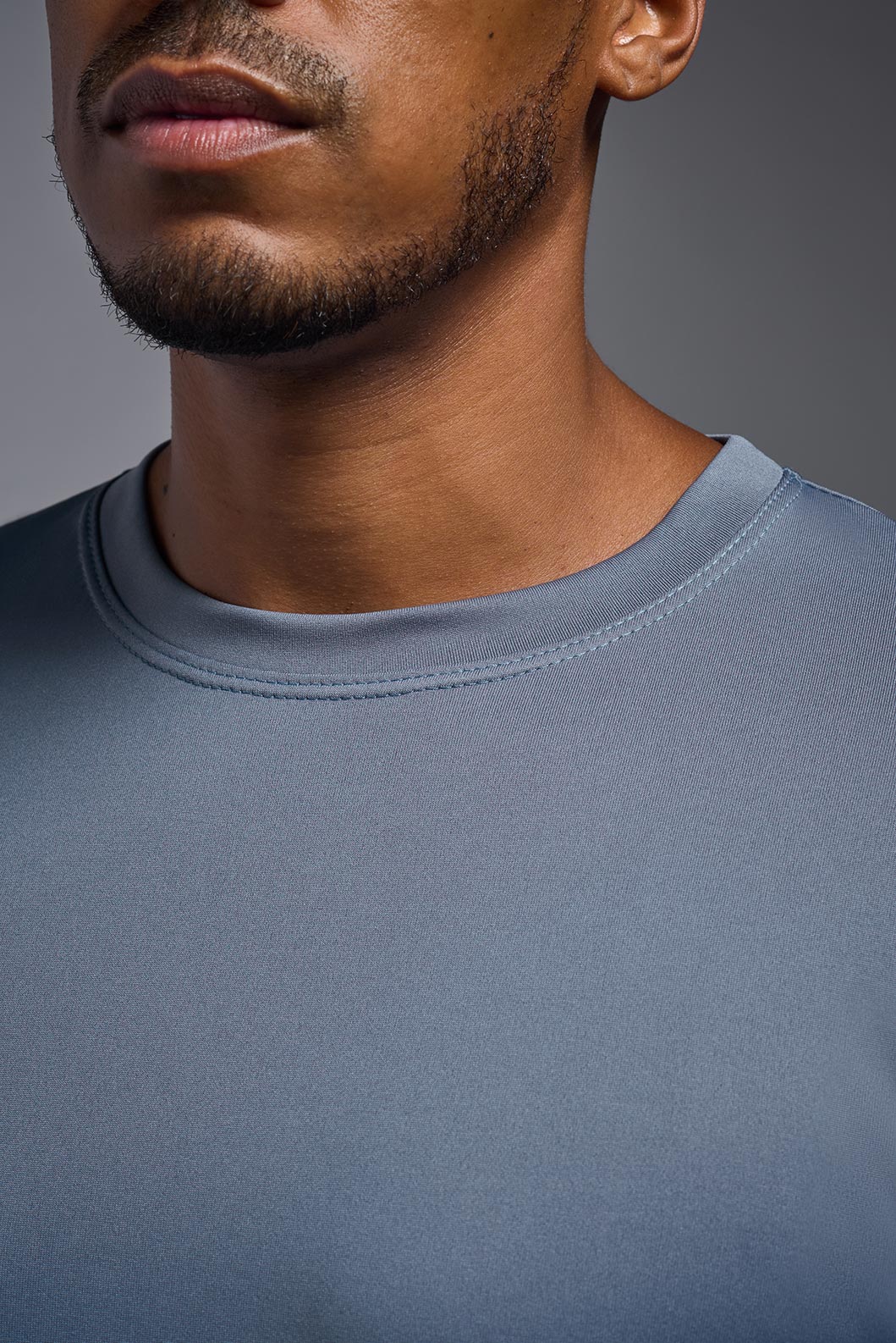 A male model wearing the men's EcoTek™ Recycled Performance Tee in the color tahoe, made out of 100% recycled polyester REPREVE®, showing the modern fit from a collar close-up view. This shirt features a mechanical stretch, quick-dries, wicks moisture and is made in the USA. #tahoe