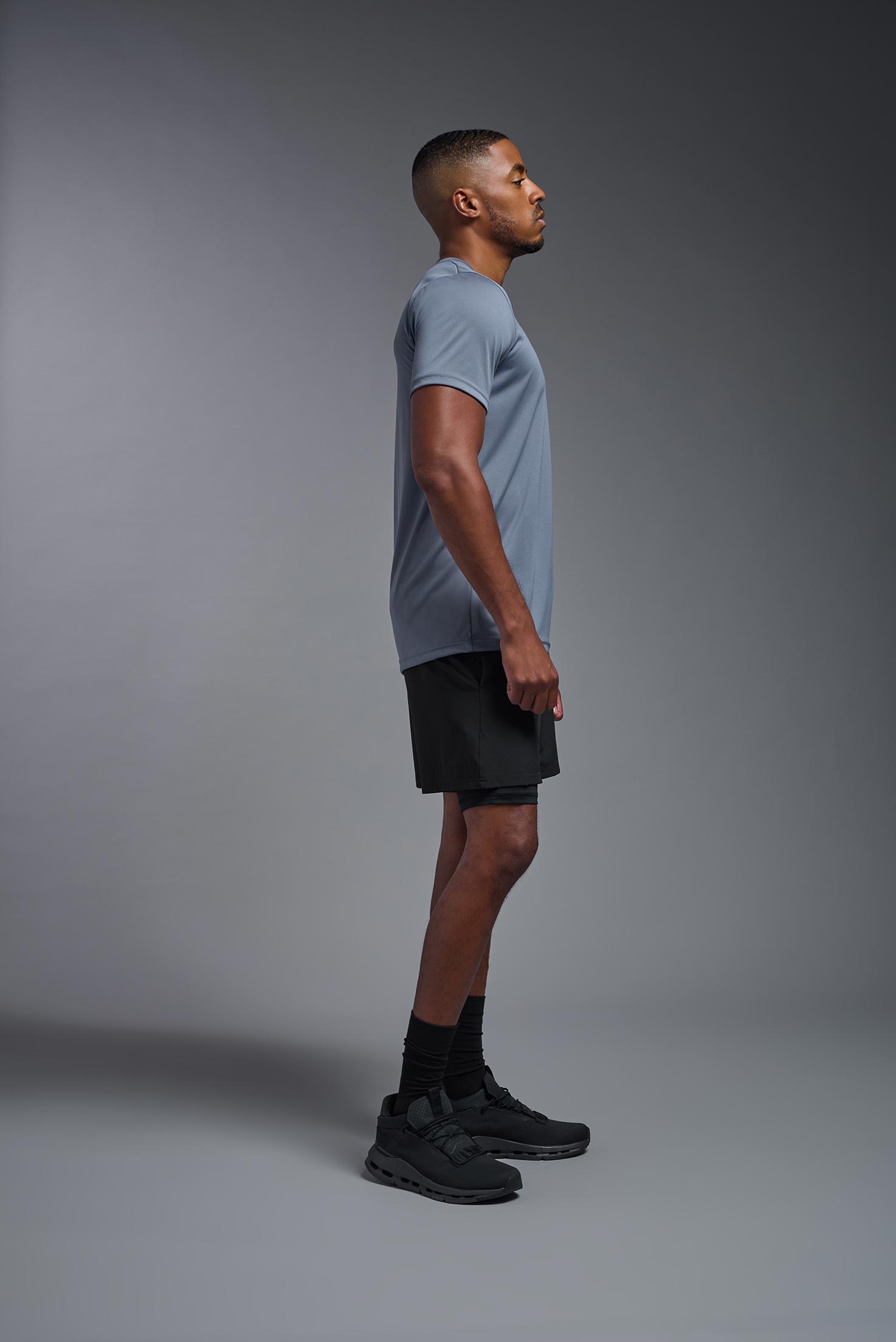 A male model wearing the men's EcoTek™ Recycled Performance Tee in the color tahoe, made out of 100% recycled polyester REPREVE®, showing the modern fit from a side view. This shirt features a mechanical stretch, quick-dries, wicks moisture and is made in the USA. #tahoe