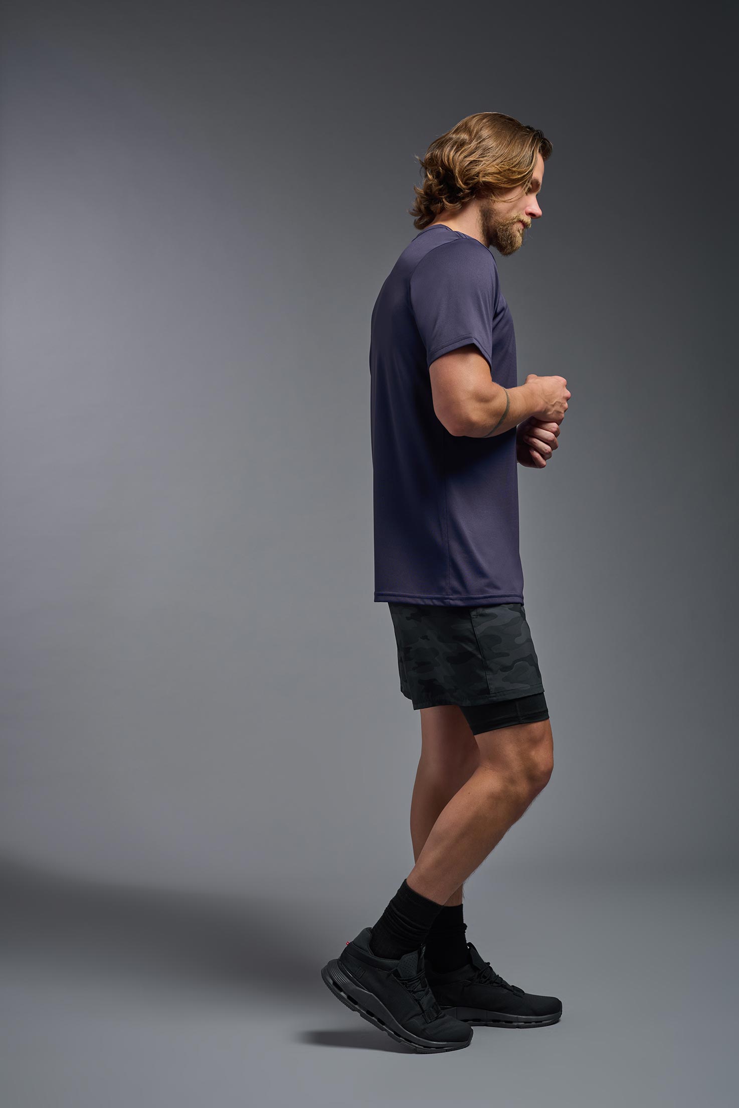 A male model wearing the men's EcoTek™ Recycled Performance Tee in the color twilight, made out of 100% recycled polyester REPREVE®, showing the modern fit from a side view. This shirt features a mechanical stretch, quick-dries, wicks moisture and is made in the USA. #twilight